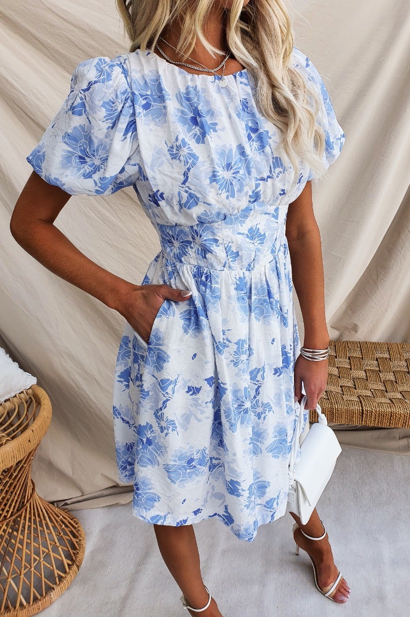Floral print dress with puff sleeves and pockets, modeled by a woman, perfect for casual outings.