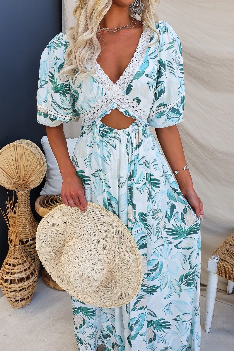 Model wearing the Out Of Sight Maxi Dress, featuring floral print, V-neckline, and cut-out waist detail.