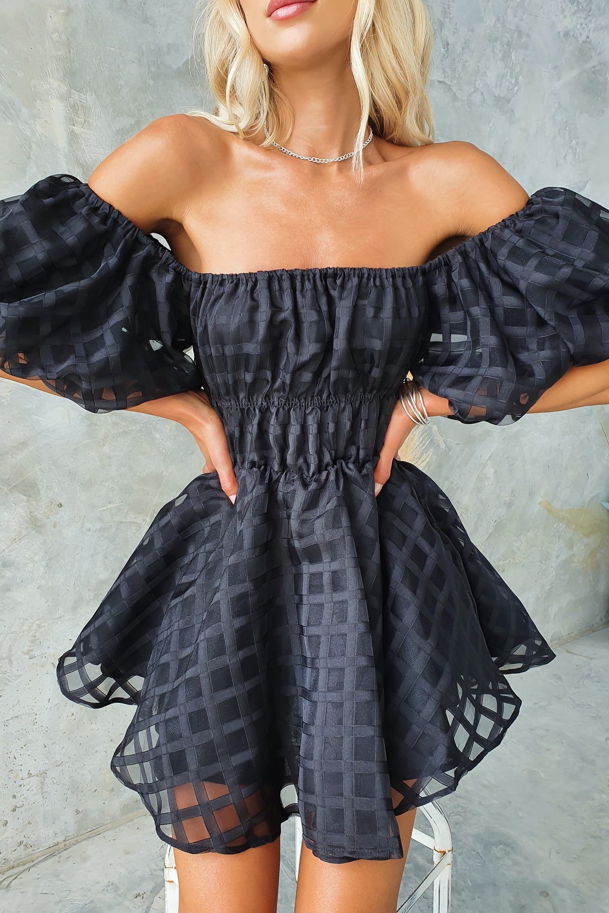 Zerali off-shoulder black dress with puff sleeves and a fitted waist, displaying a stylish and chic silhouette.