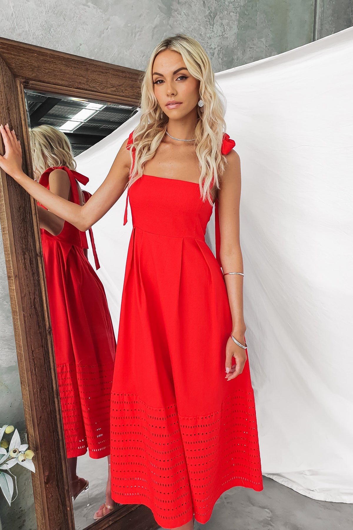 Woman wearing a red Wileman Midi Dress with adjustable tie straps and a lined, mid-thigh design.