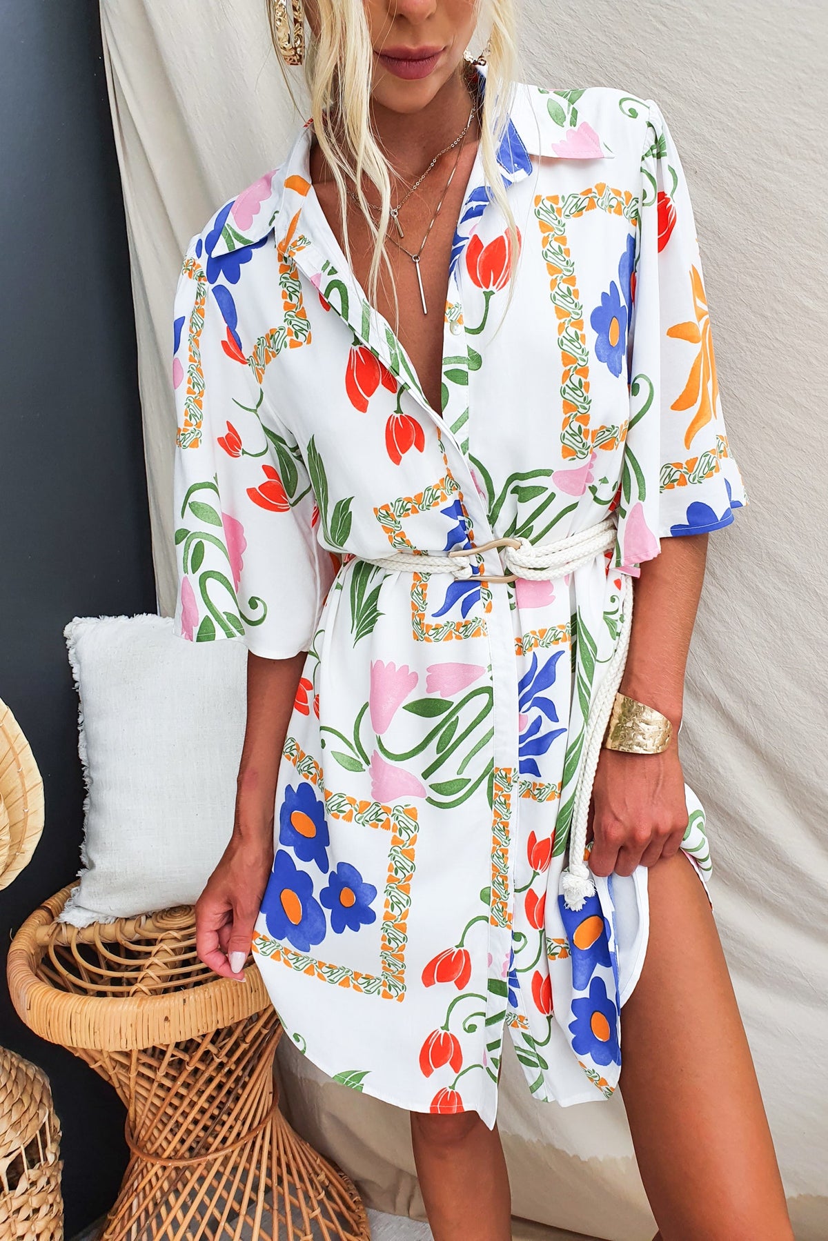 Model wearing a colorful abstract print dress with a collar, button-up front, and removable belt.