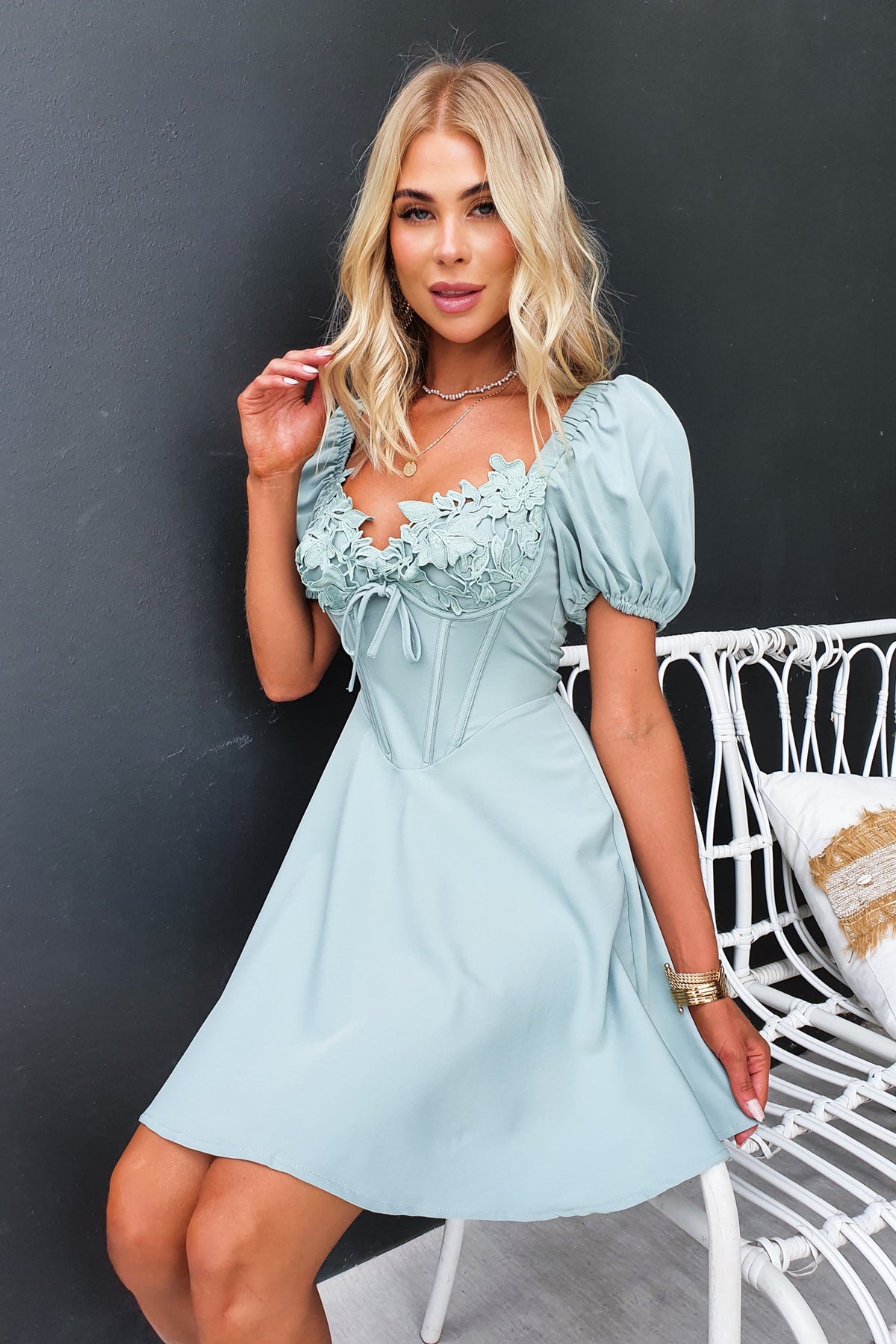 Model wearing a light blue Nonny Dress with lace detail and puff sleeves, featuring an elegant bust design.