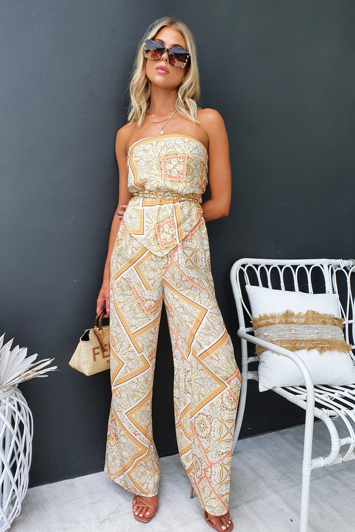 Fashionable model wearing Vivid Pants with an abstract print, styled with sunglasses and a bag, against a chic background.