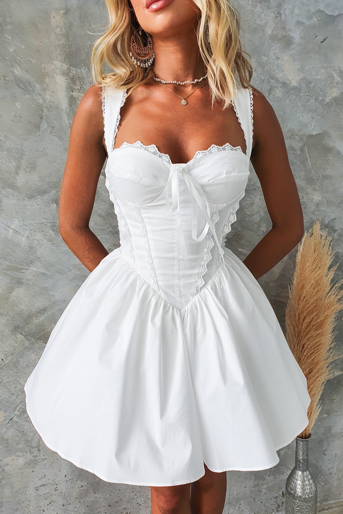 Cevallo Dress: White dress with lace detail, tie bust, and flared skirt, perfect for summer occasions.