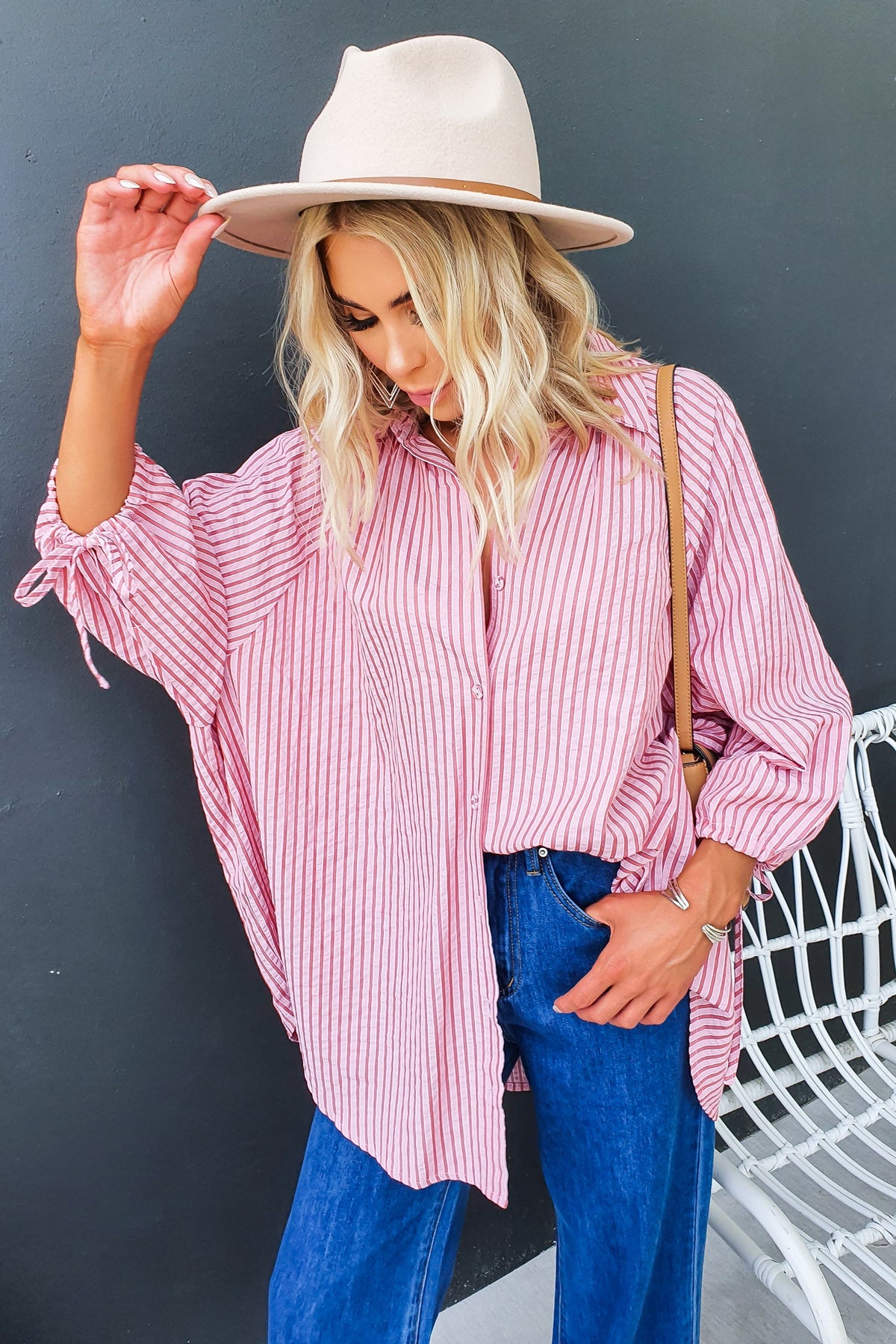 Model wearing a pink striped Sorbet Shirt with tie sleeve details, paired with blue jeans and a beige hat.