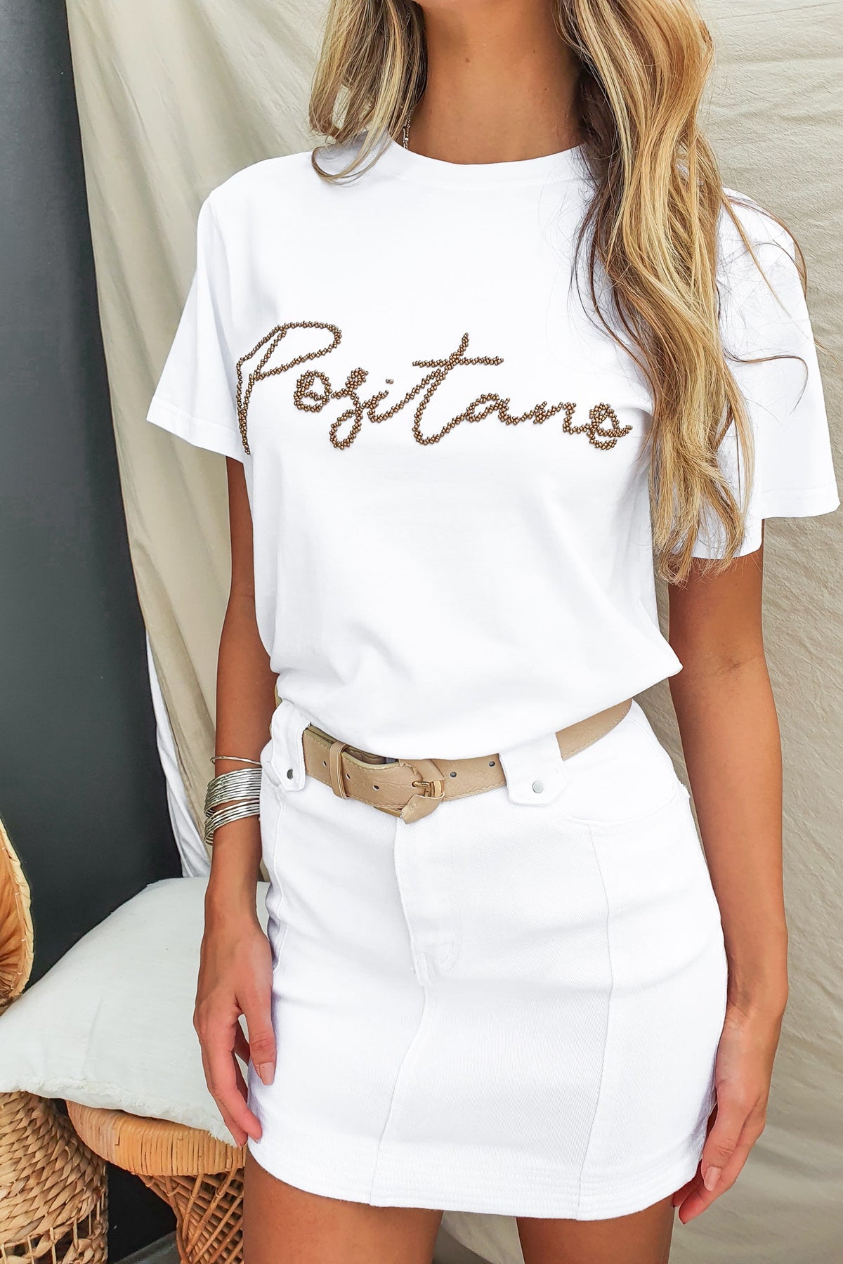 Model wearing the Landon Tee in white with 'Positano' bead detail, styled with a fitted skirt.
