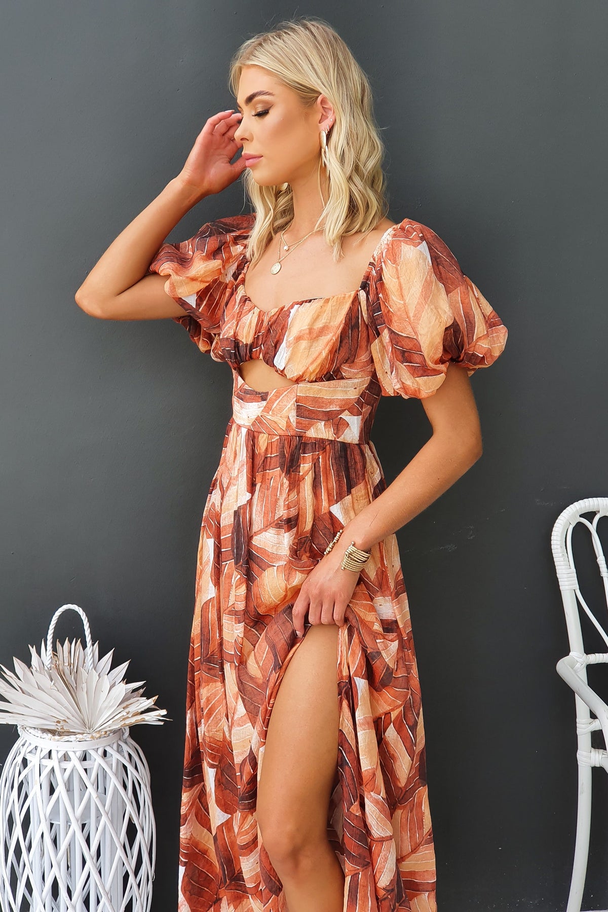 Model wearing Damaris Maxi Dress with puff sleeves and cut-out, featuring a front split in a vibrant floral print.