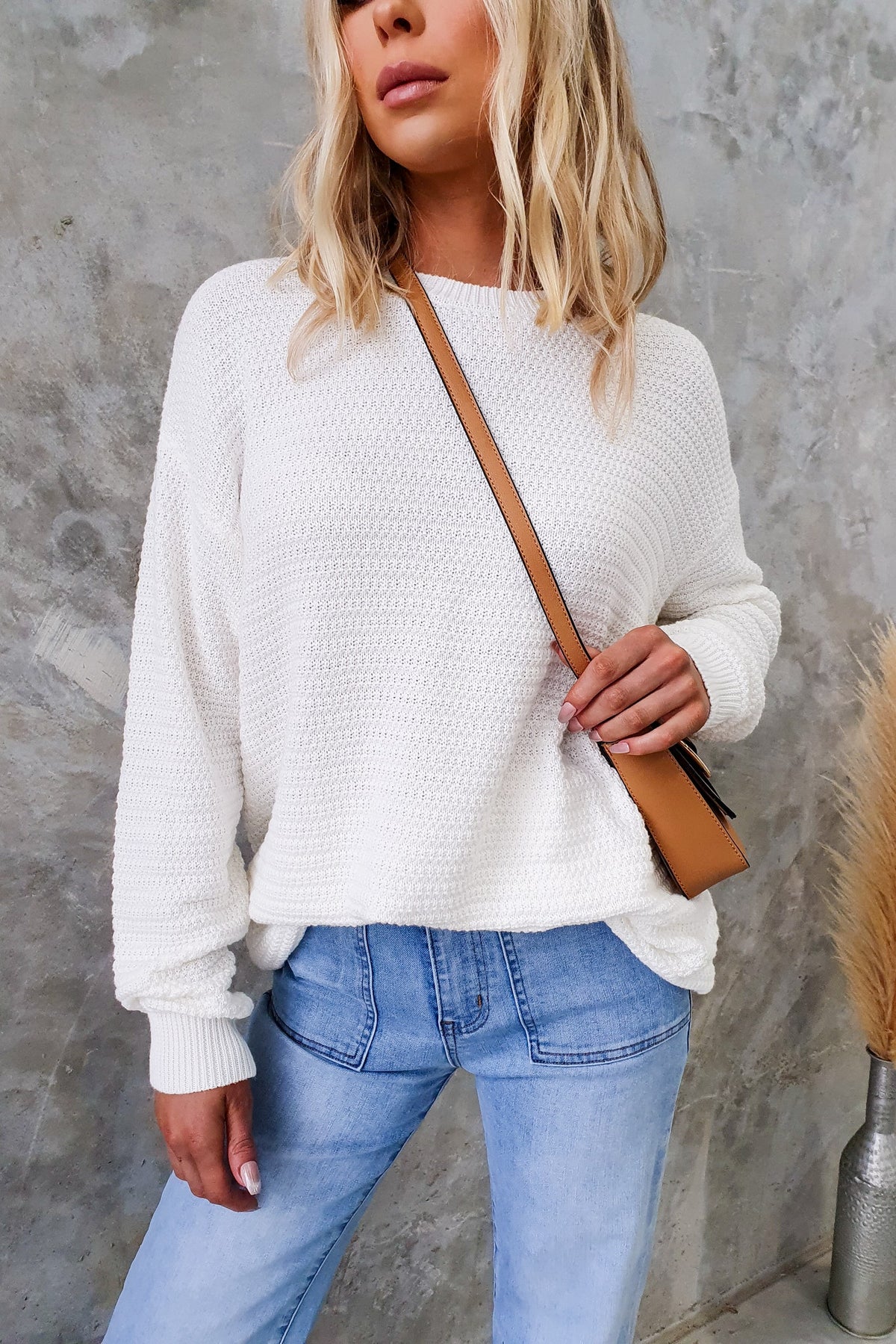 White knit Rhode Jumper with round neckline, styled casually with denim jeans and a brown bag.