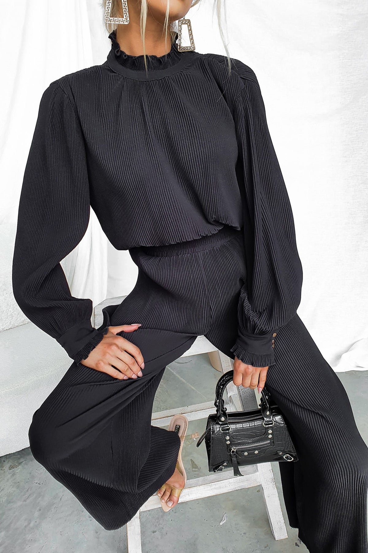 Barbara Top in black, high neckline, pleated material, featuring relaxed fit, styled with chic accessories.