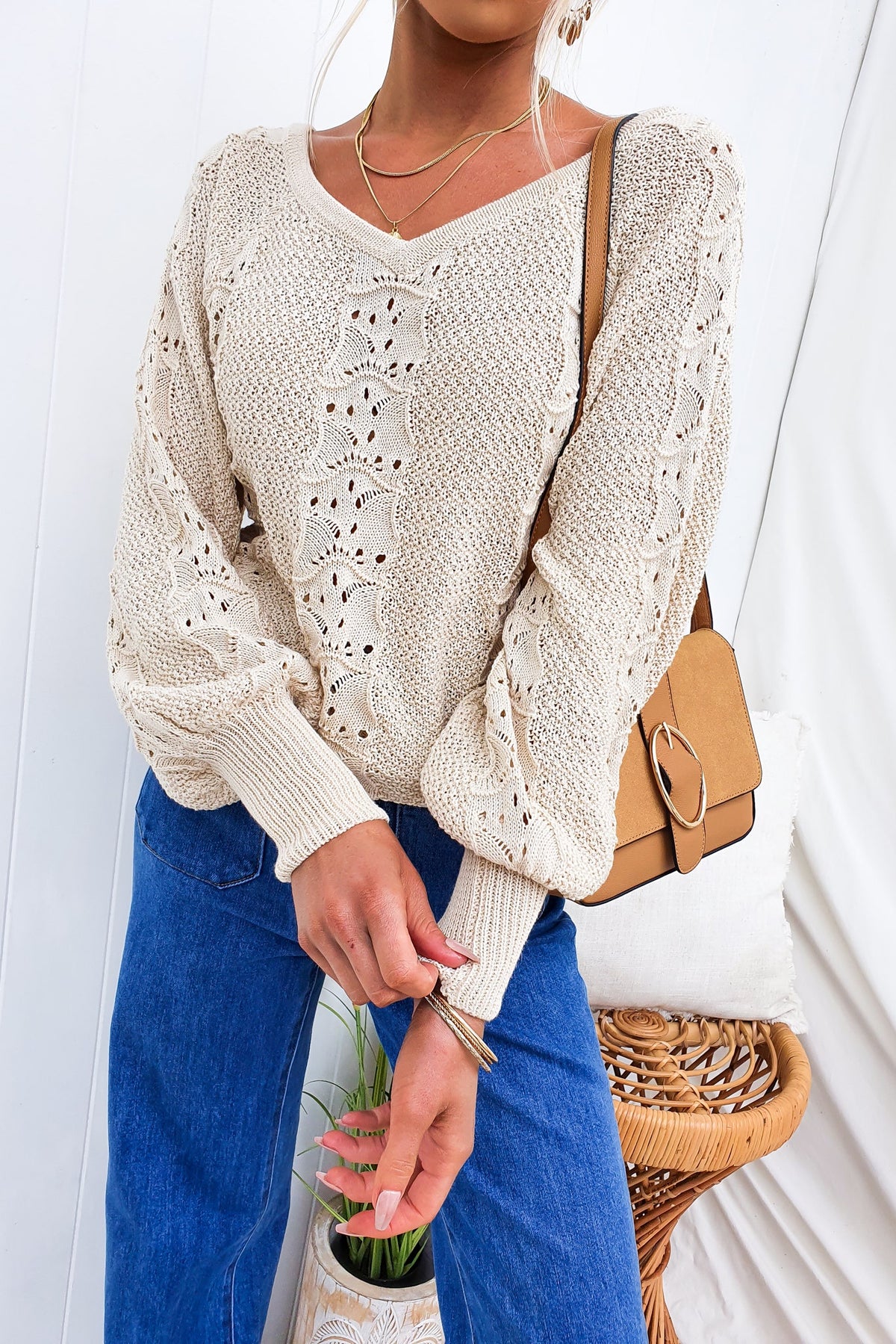 Cadie Knit V-neck top in beige with semi-open weave, styled with blue jeans and a tan bag.