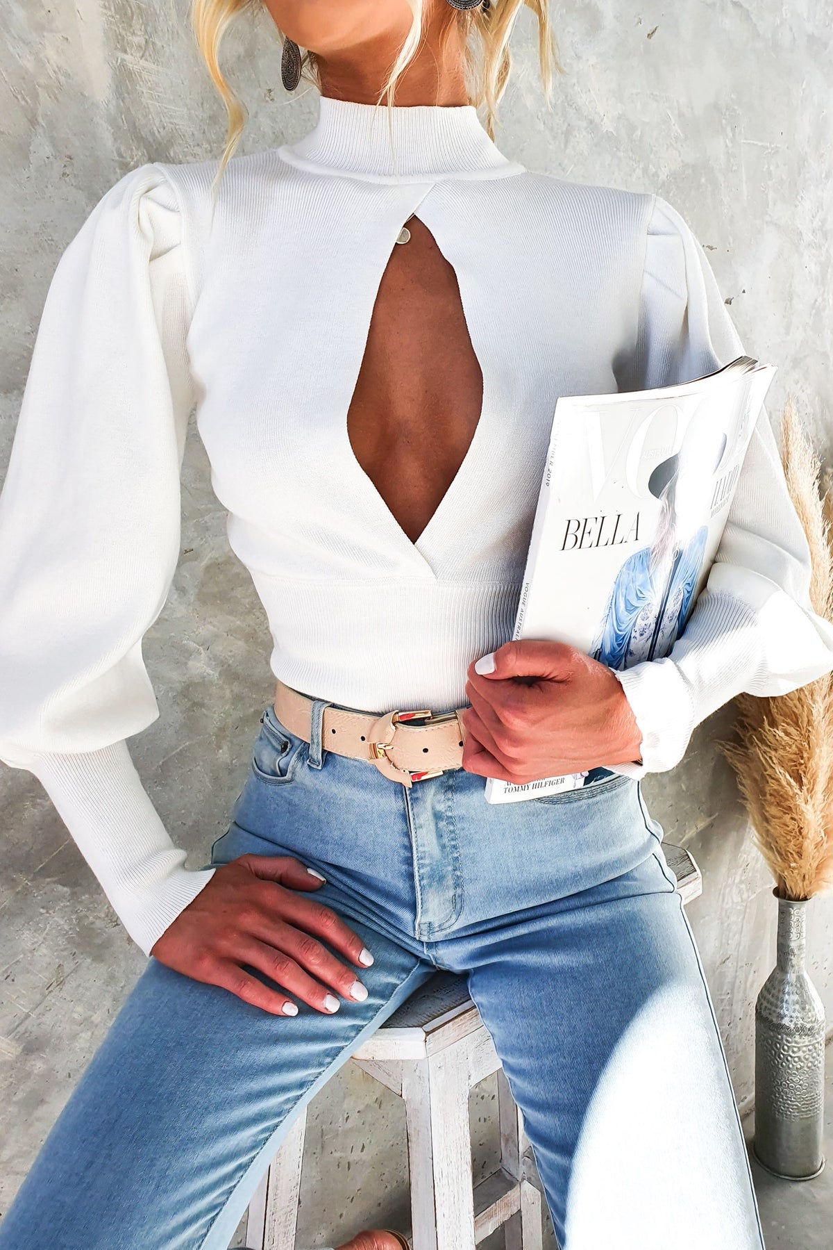 Sania Top featuring high neckline and cut-out bust, worn with high-waisted jeans, styled with a trendy belt.