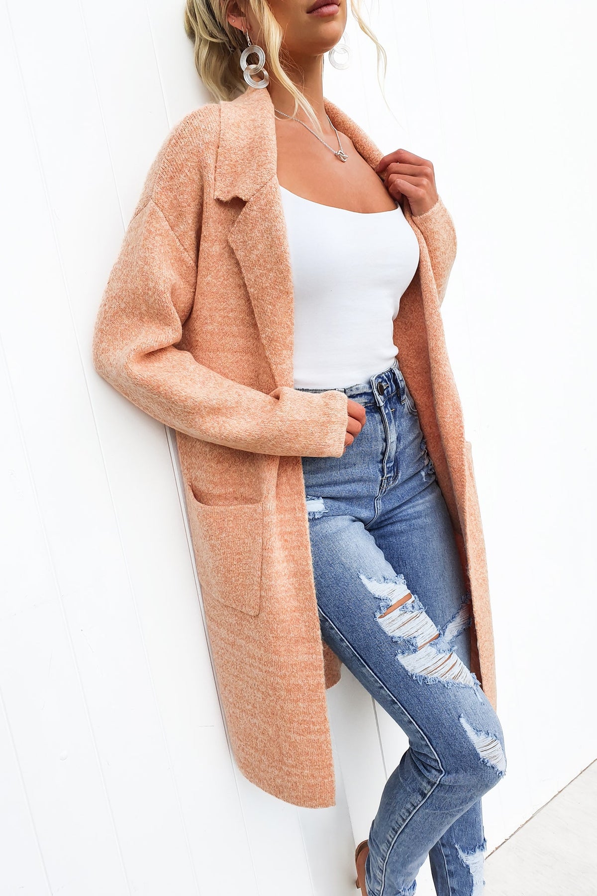 Model wearing Sarlia Cardigan in peach, styled with a white tank and ripped jeans, perfect for a relaxed look.