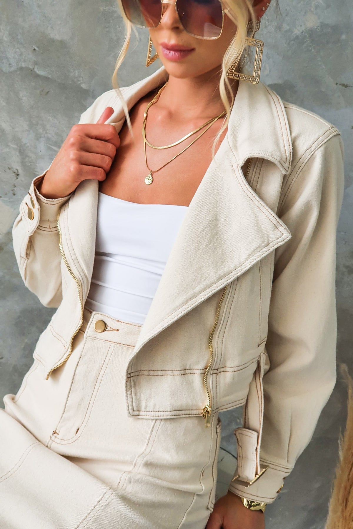 Stylish model wearing a beige denim jacket with collar, zip-up front, and cropped fit, paired with a white top.