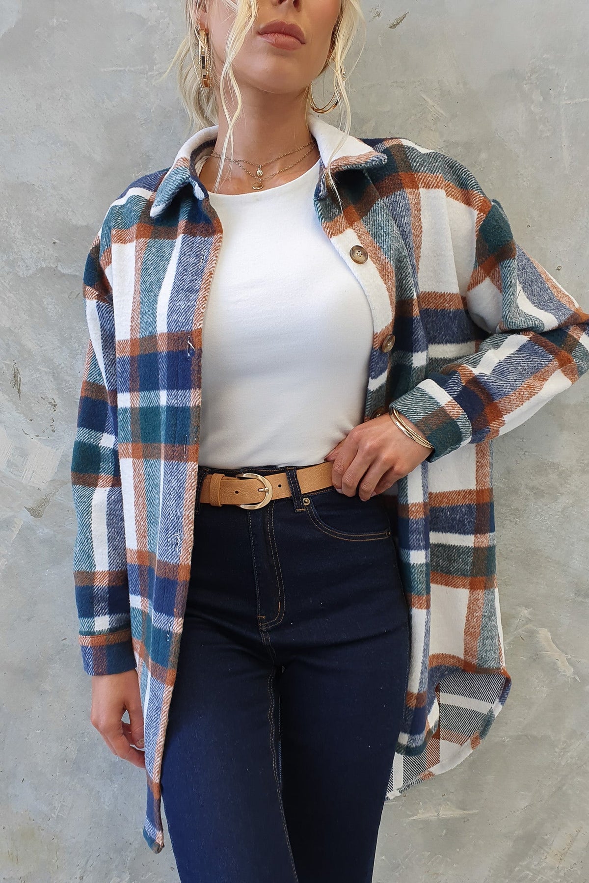 Model wearing a Braedyn shacket, featuring a plaid pattern, button-up style, and high-low hem with jeans.