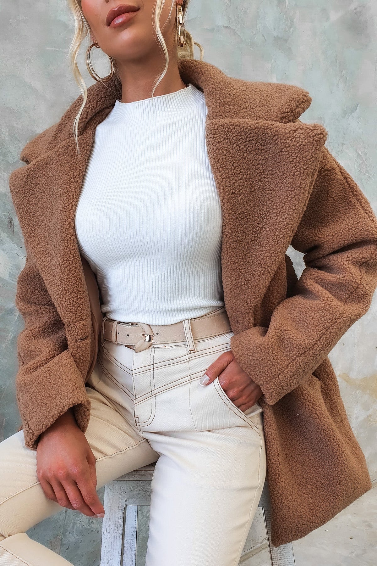 Stylish woman wearing a Phala Coat in teddy material, paired with a white top and cream pants.