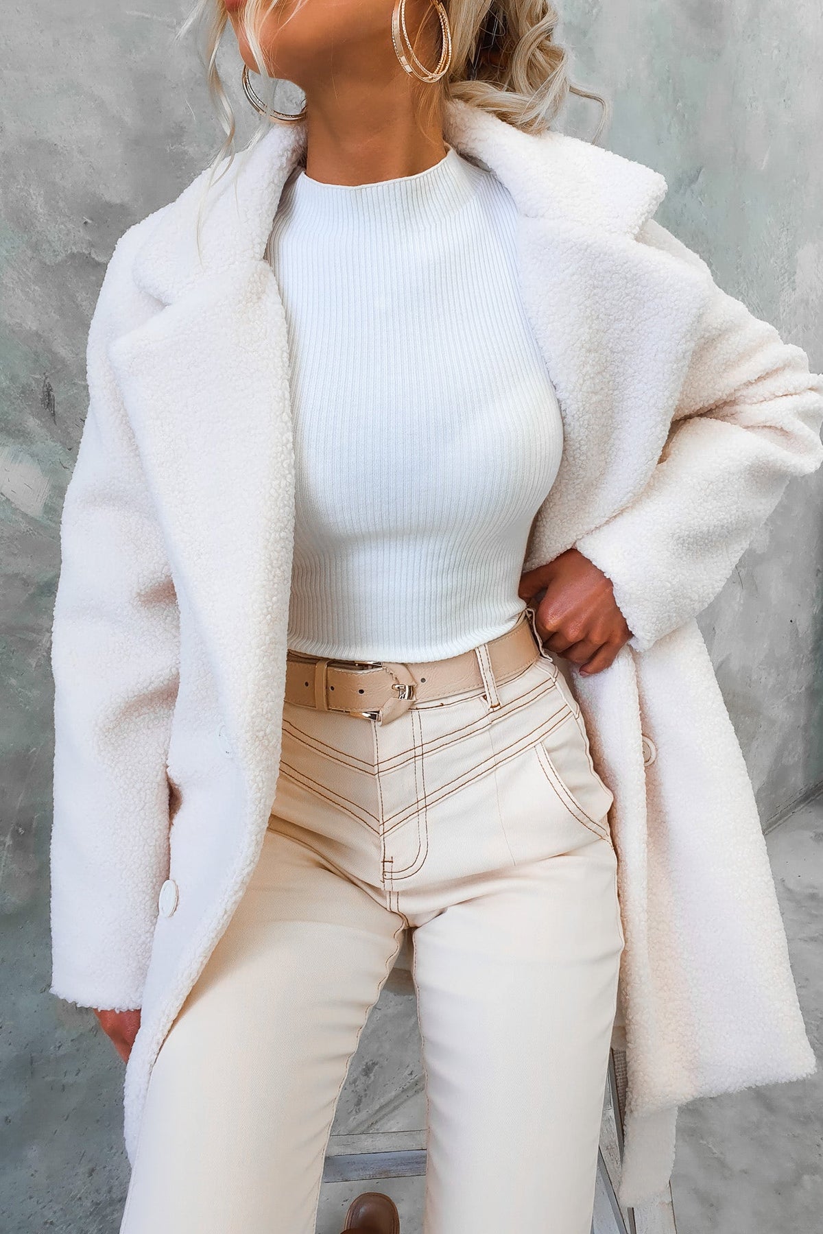 Model wearing a cozy white teddy coat over a fitted white top and cream jeans, showcasing a stylish winter look.