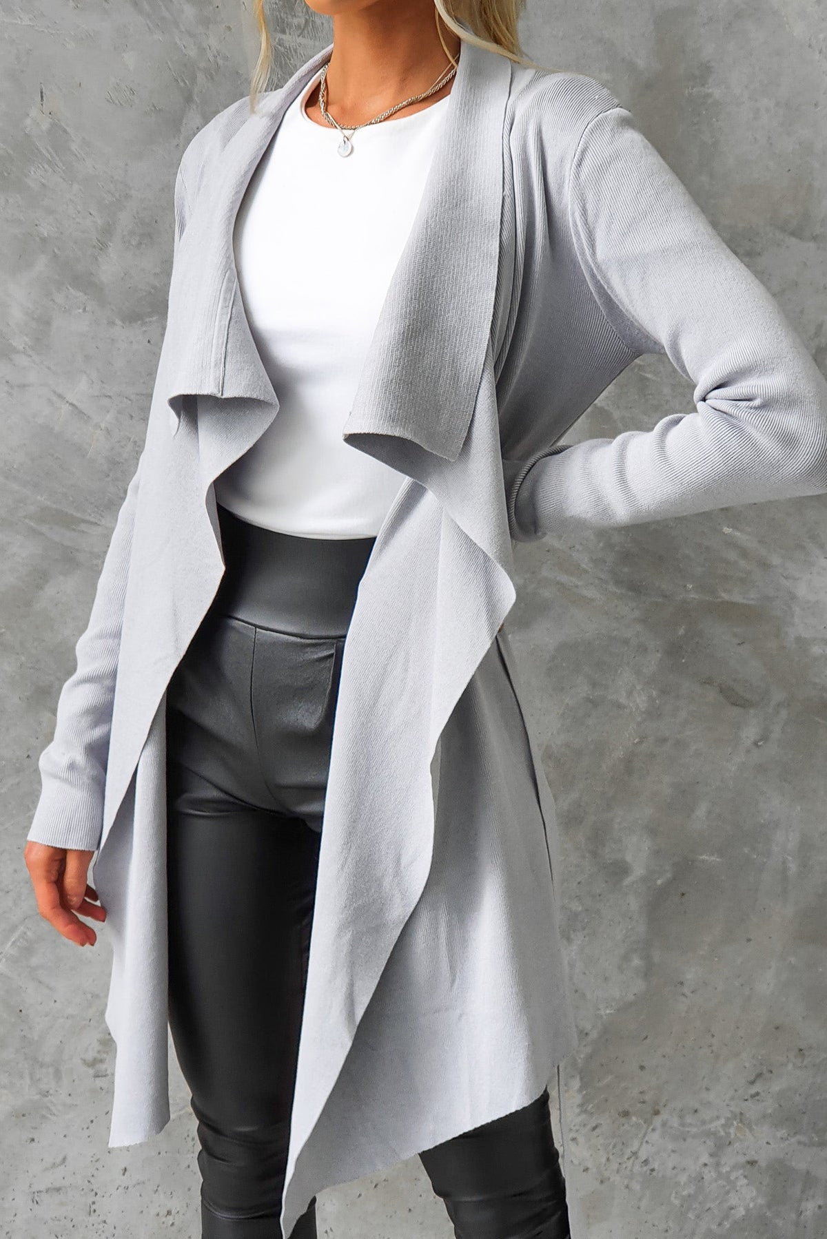 Stylish grey Acaia cardigan featuring a draped collar, lapel, and a relaxed fit, paired with black faux leather pants.