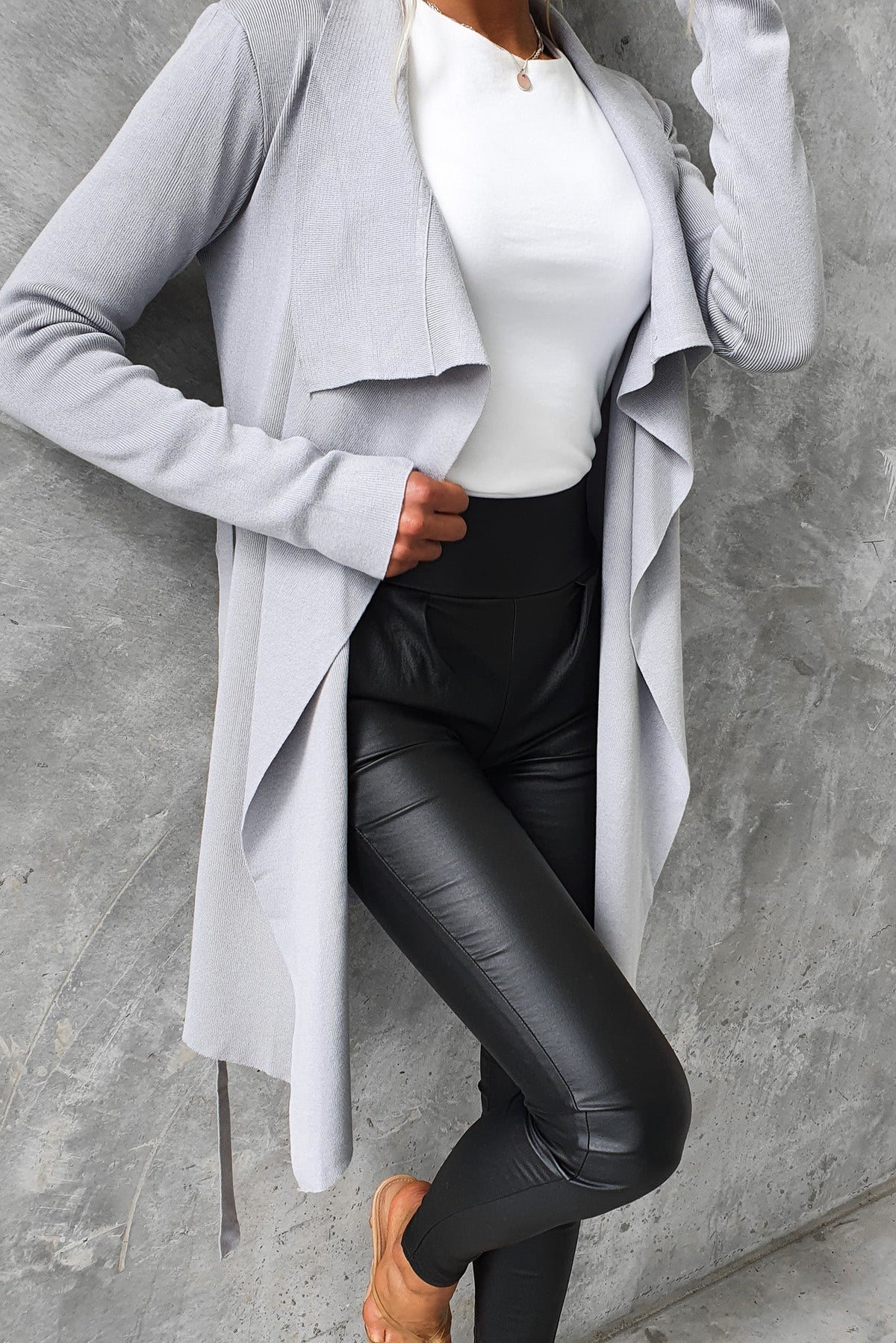 Acaia cardigan in light gray, layered drape design, paired with black faux leather pants.