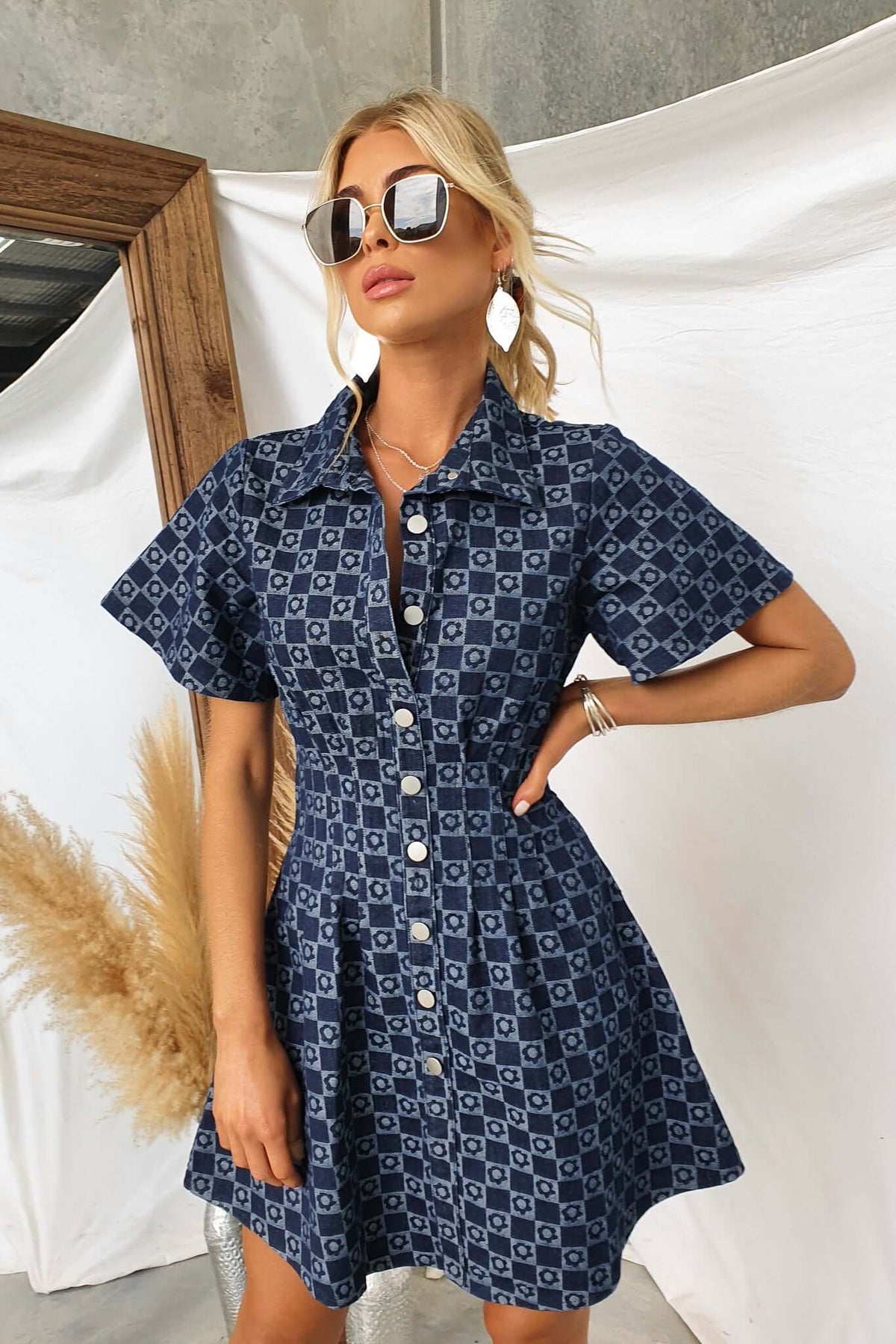 Model in a Mara Denim Dress featuring a button-up front and short sleeves, styled with sunglasses.