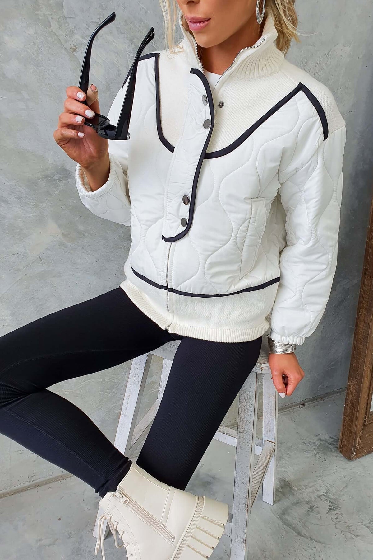Stylish Carota Jacket featuring high neck, quilted design, front buttons, and elastic sleeves, paired with black leggings.