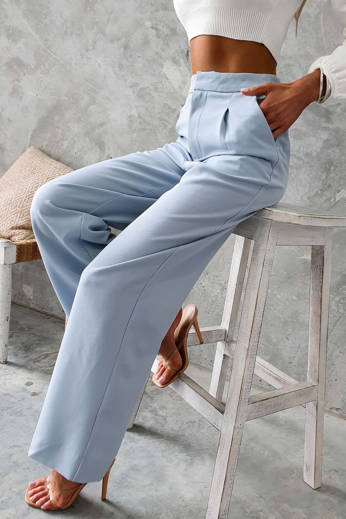 Kodi Pants in light blue with a mid-high waist, wide legs, and pockets, styled with a white crop top and high heels.