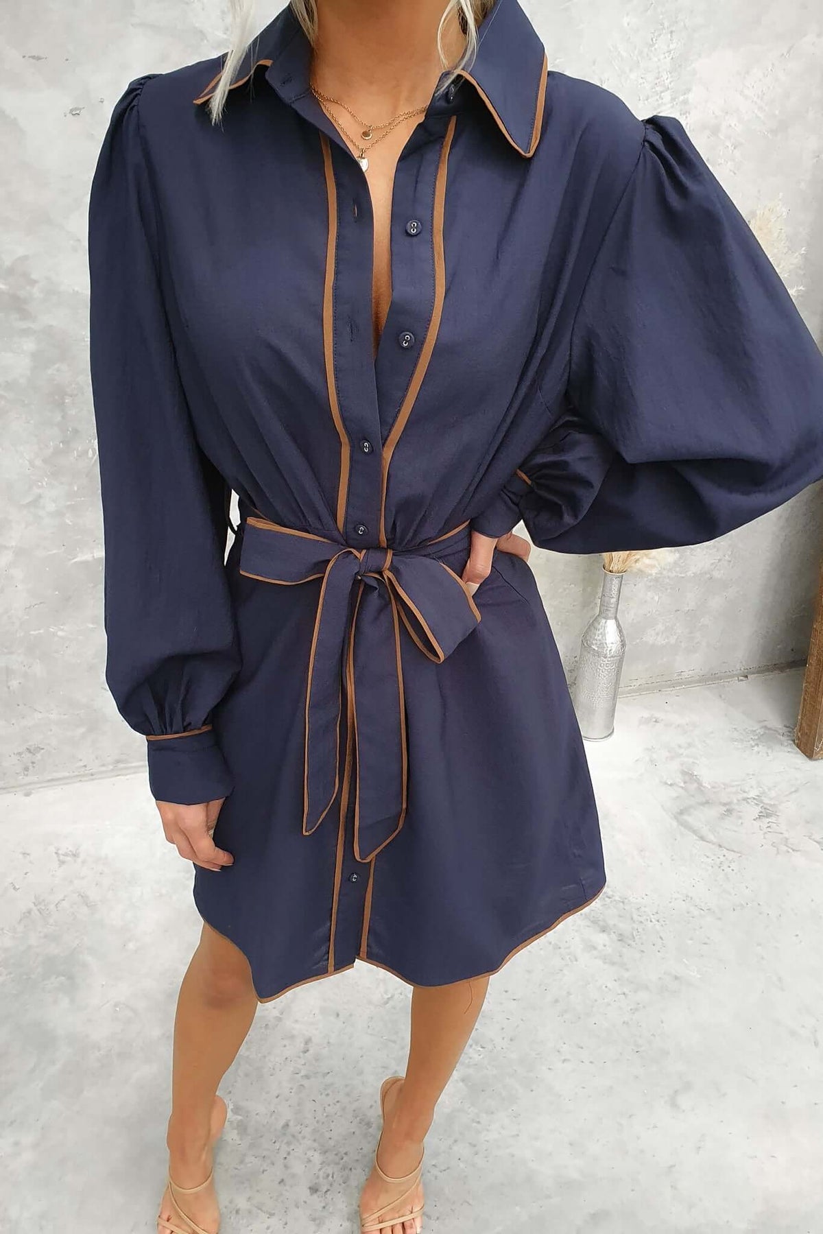 Navy Pianolo Dress featuring a button-up front, collar, elastic sleeves, and a removable tie detail.