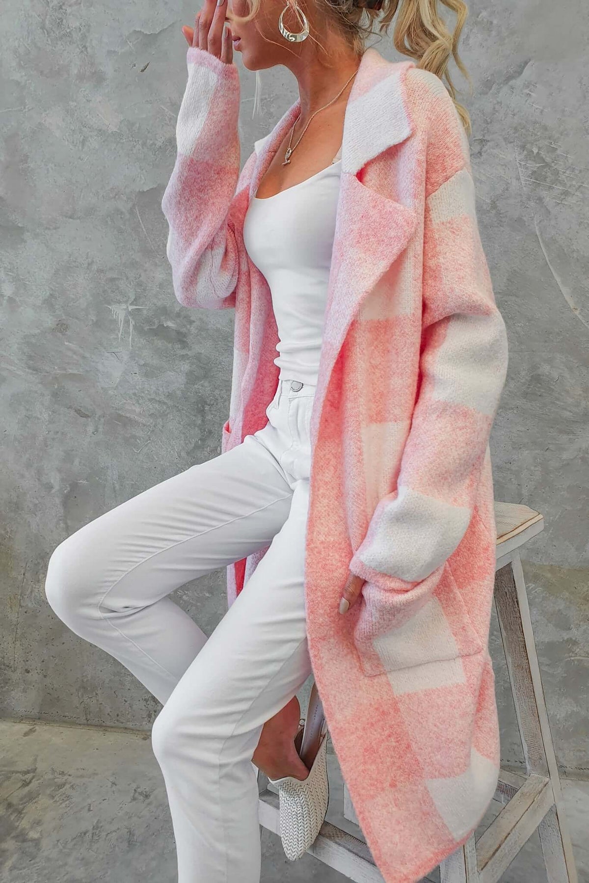 Model wearing a pink and white longline Fatale Cardigan with pockets, styled with white pants and a tank top.