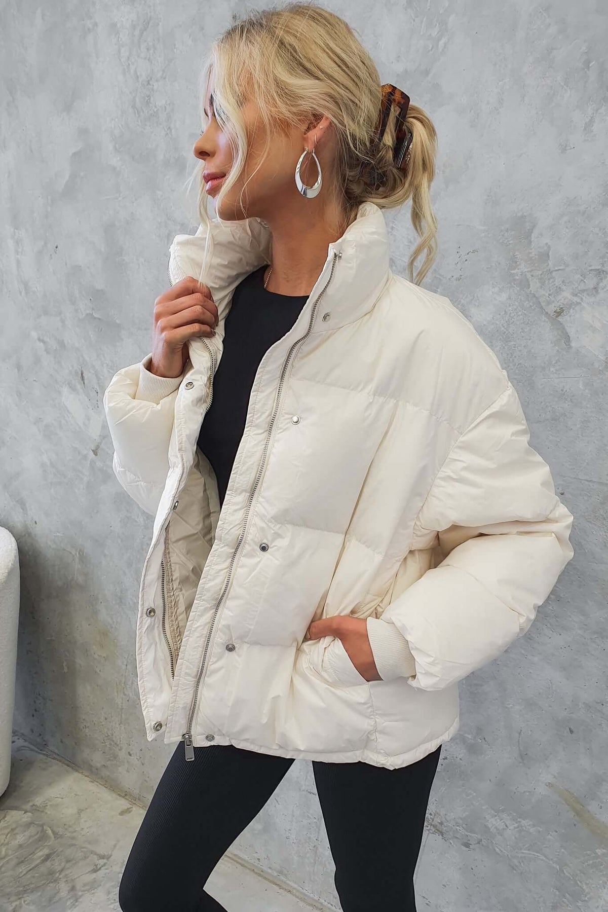 Model wearing a chic white Cooper puffer jacket with a high neckline, side pockets, and elastic cuffs.