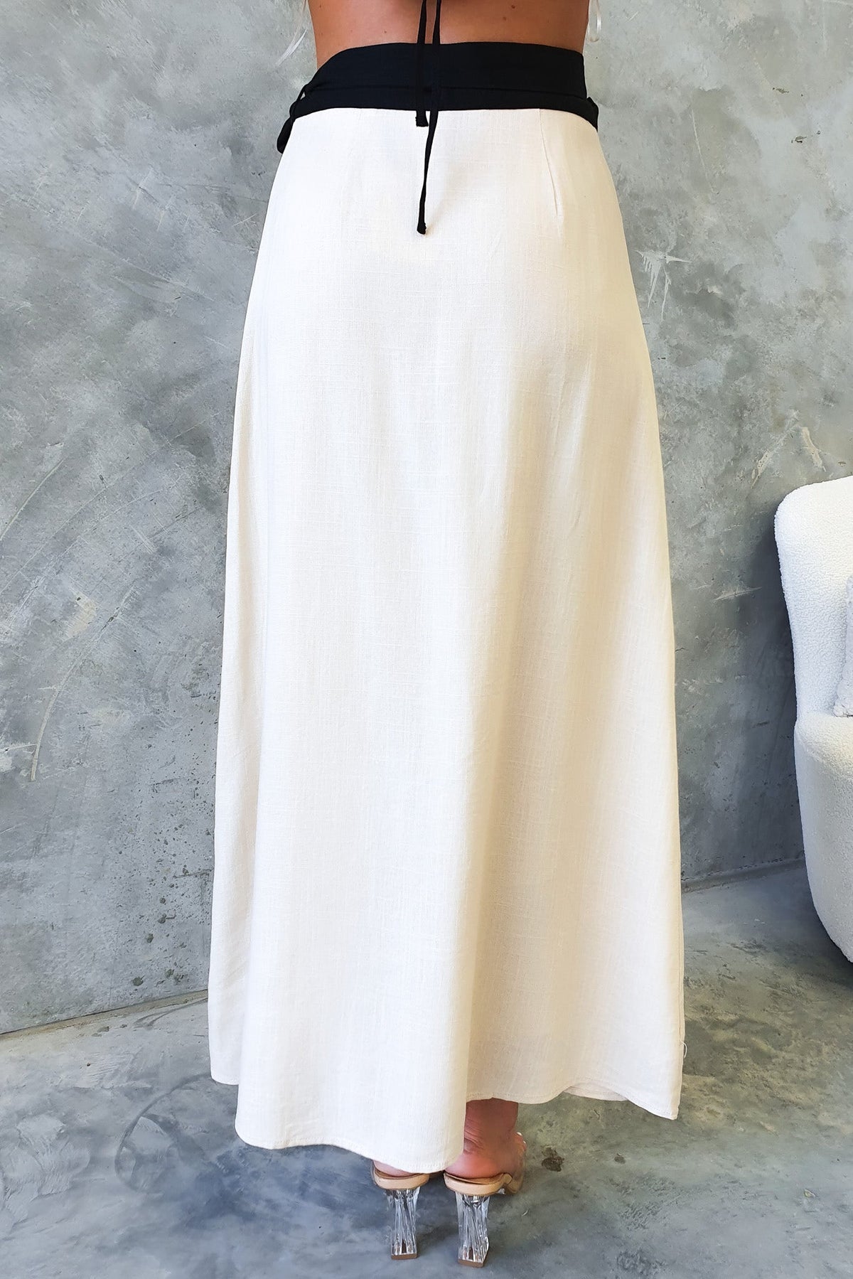Back view of a Tuscan Wrap Maxi Skirt with a black waistband, showcasing the flowy design and asymmetric hemline.