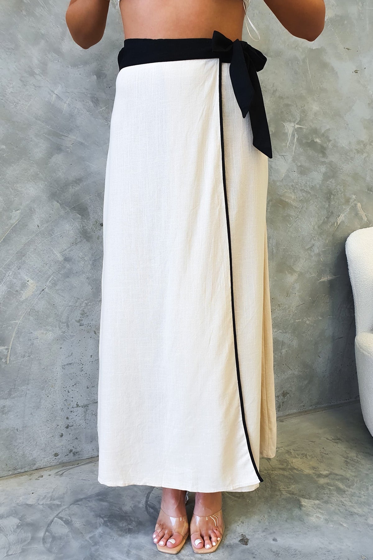 Tuscan Wrap Maxi Skirt featuring an asymmetric hemline and a stylish black tie belt, perfect for a chic summer look.