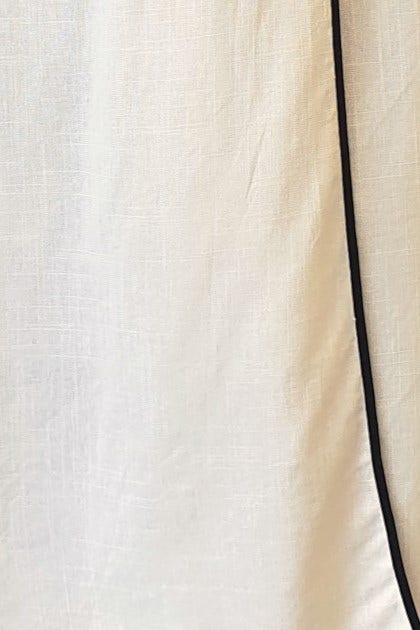 Close-up of the textured fabric of a Tuscan Wrap Maxi Skirt, featuring a cream linen look with a black trim.