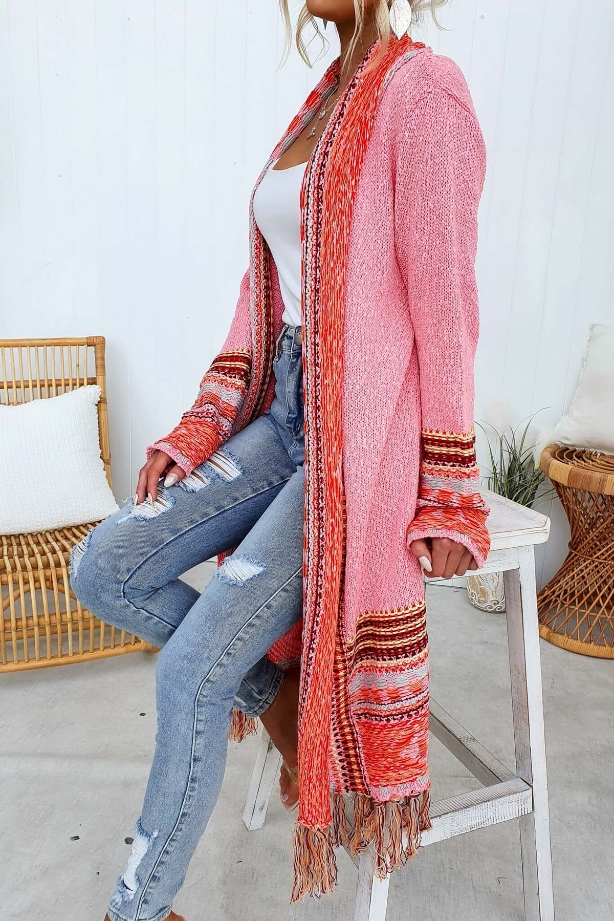 Model wearing a pink Lewis Cardigan with tassels, paired with distressed jeans, showcasing a relaxed style.
