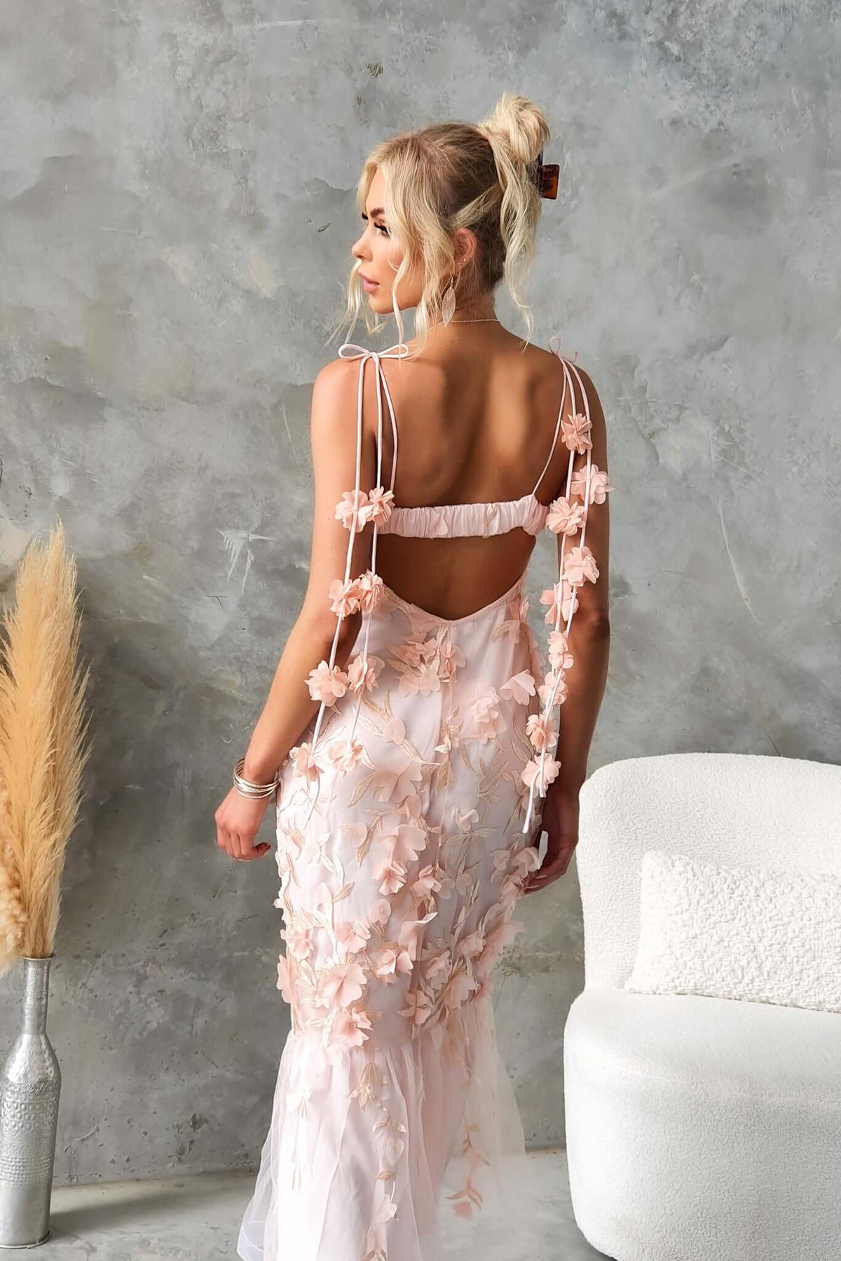 Back view of a woman in a Nephi Midi Dress with floral lace overlay and adjustable tie straps, styled with minimal decor.