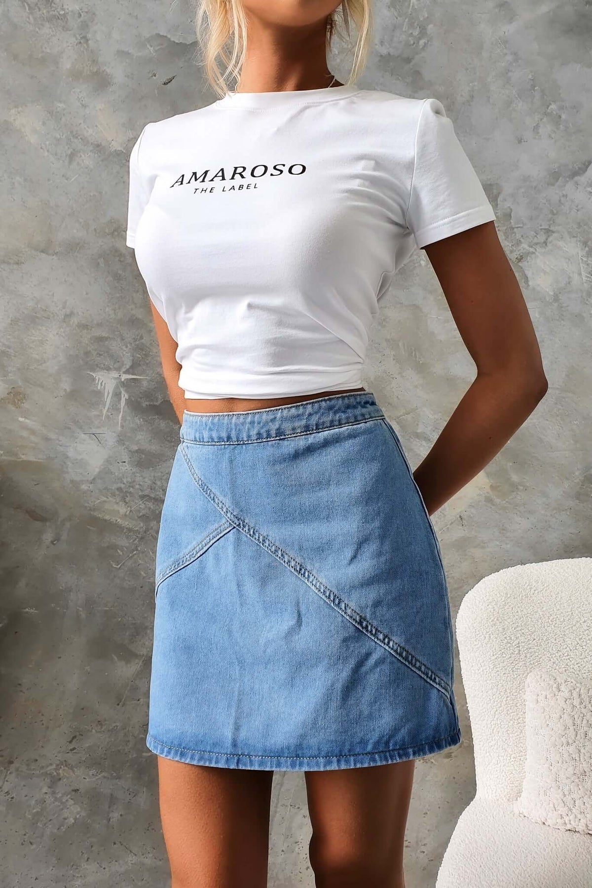 Model wearing a Lizzie denim skirt with a mid-high waist and zip at the back, styled with a fitted white tee.