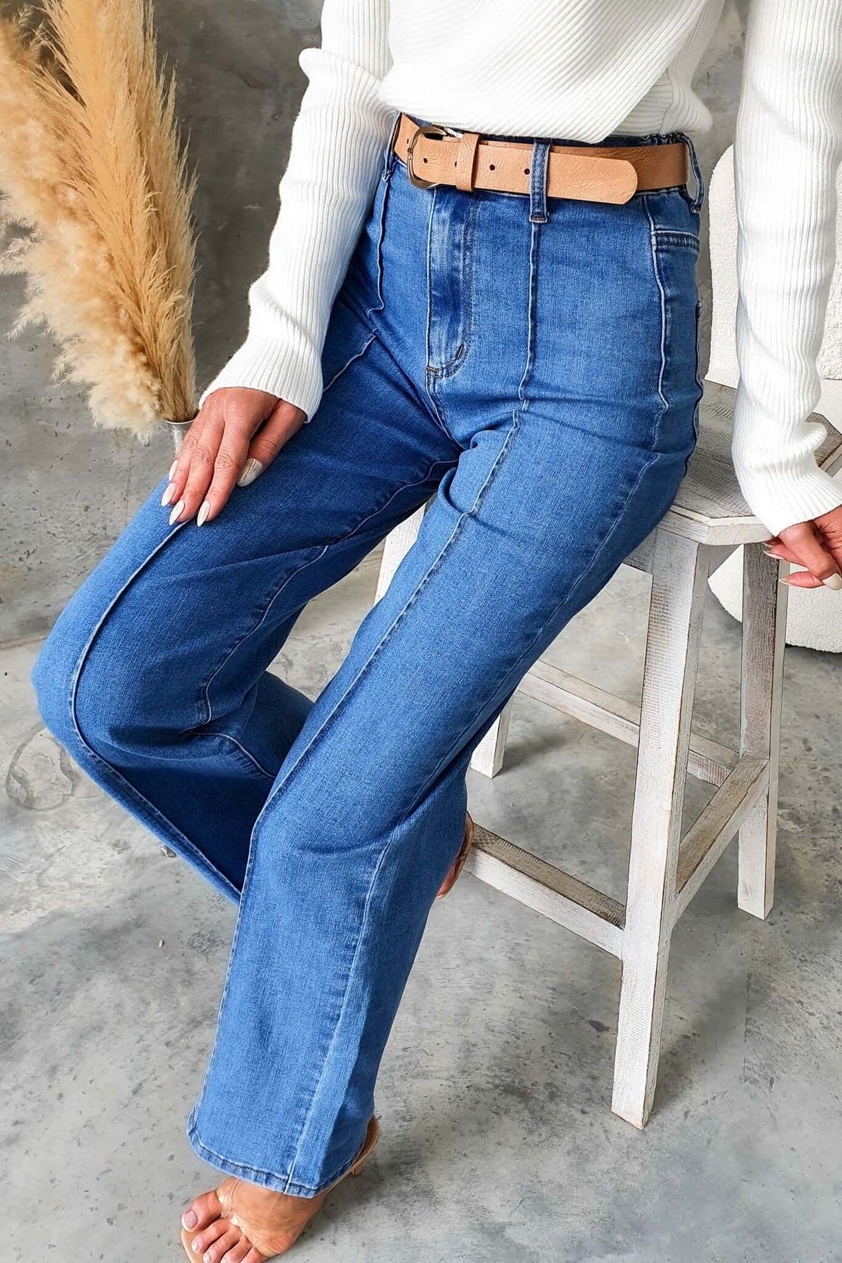 Model wearing Daffy Jeans with a mid-high waist, elastic waistband, and wide legs, styled with a belt and casual top.