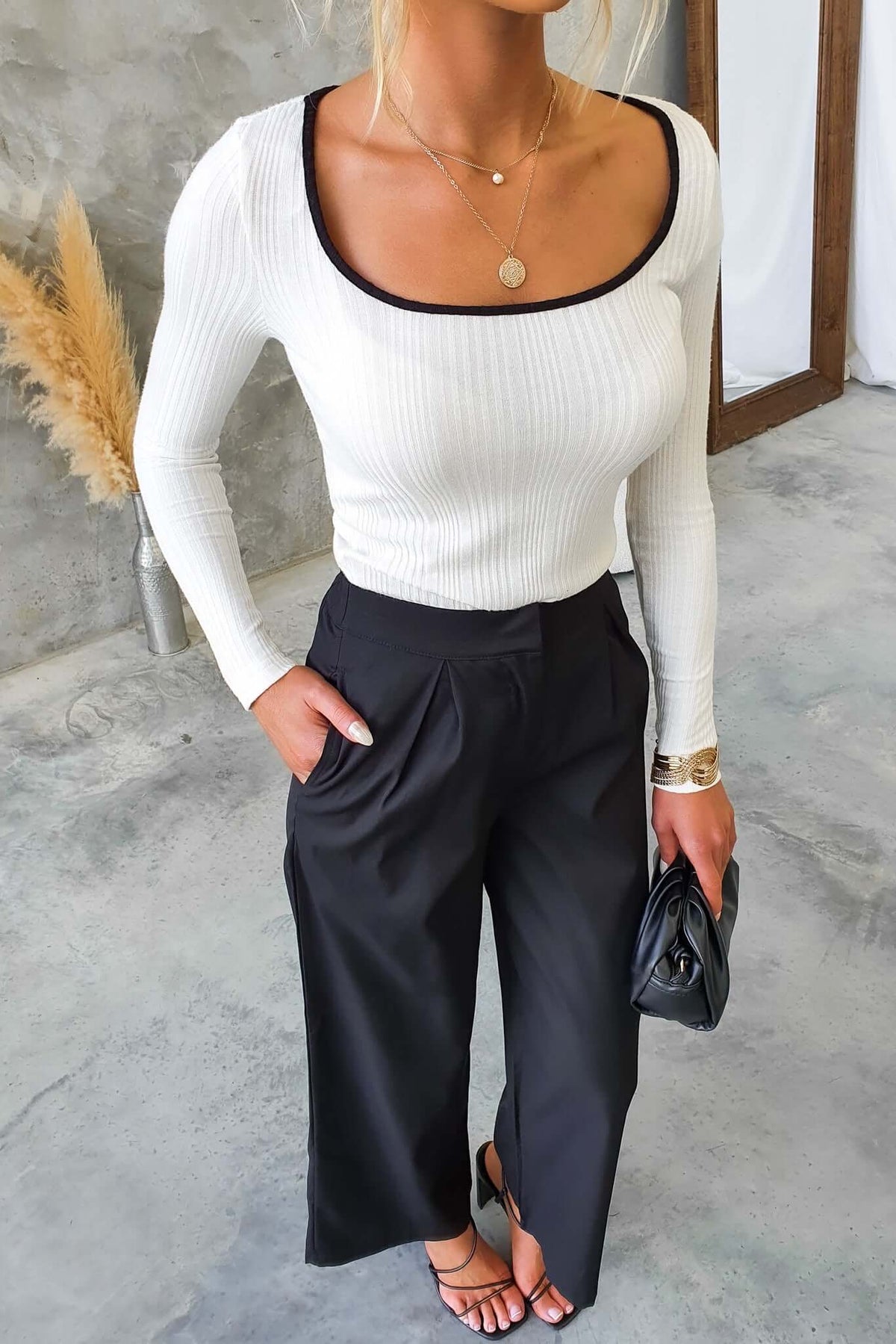 Model wearing Rayna Top, a white ribbed long-sleeve top, paired with black wide-leg pants, showcasing a chic outfit.