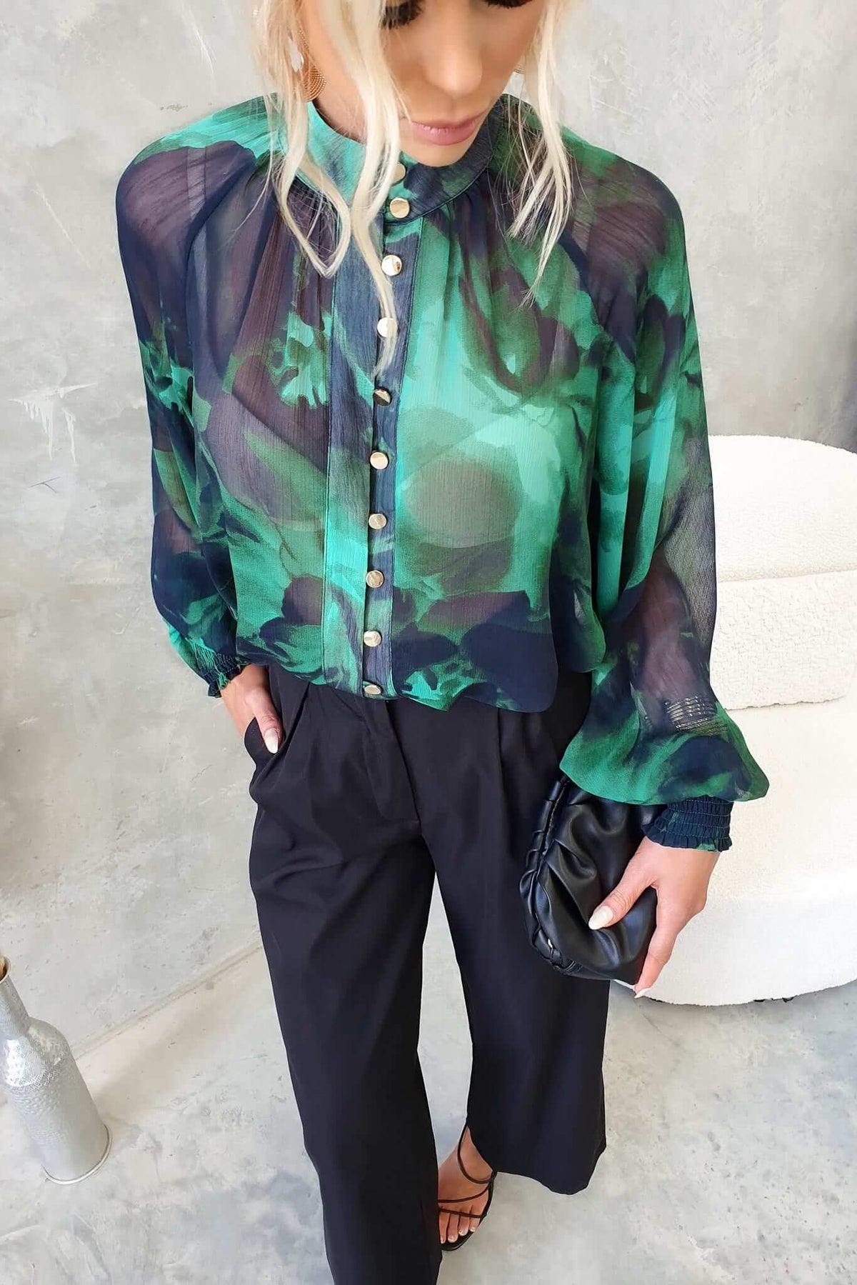 Model wearing Orazio Top featuring a high neckline, button-up front, and chiffon material in green floral pattern.