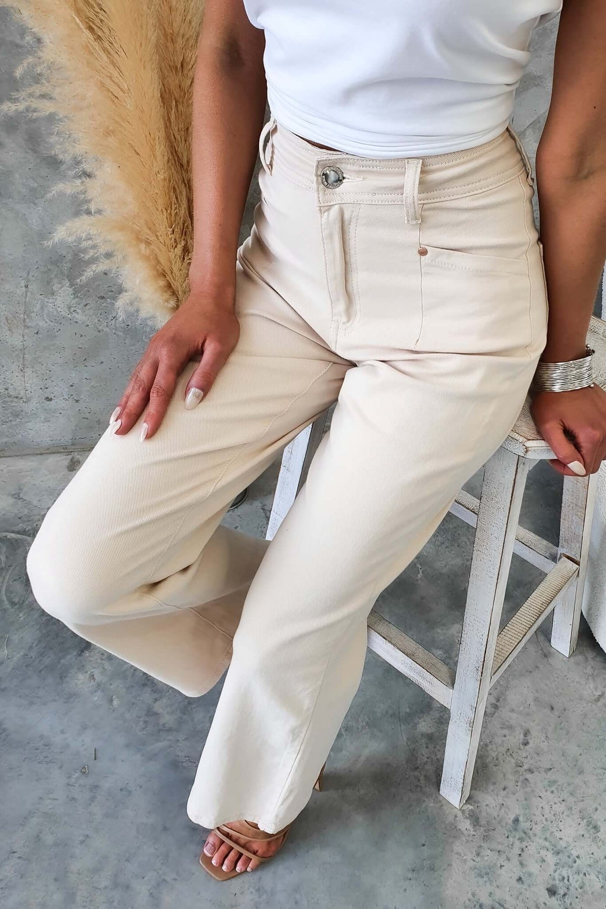 Model wearing high-waisted beige Blanca Jeans with wide legs, showcased in a stylish, trendy setting.