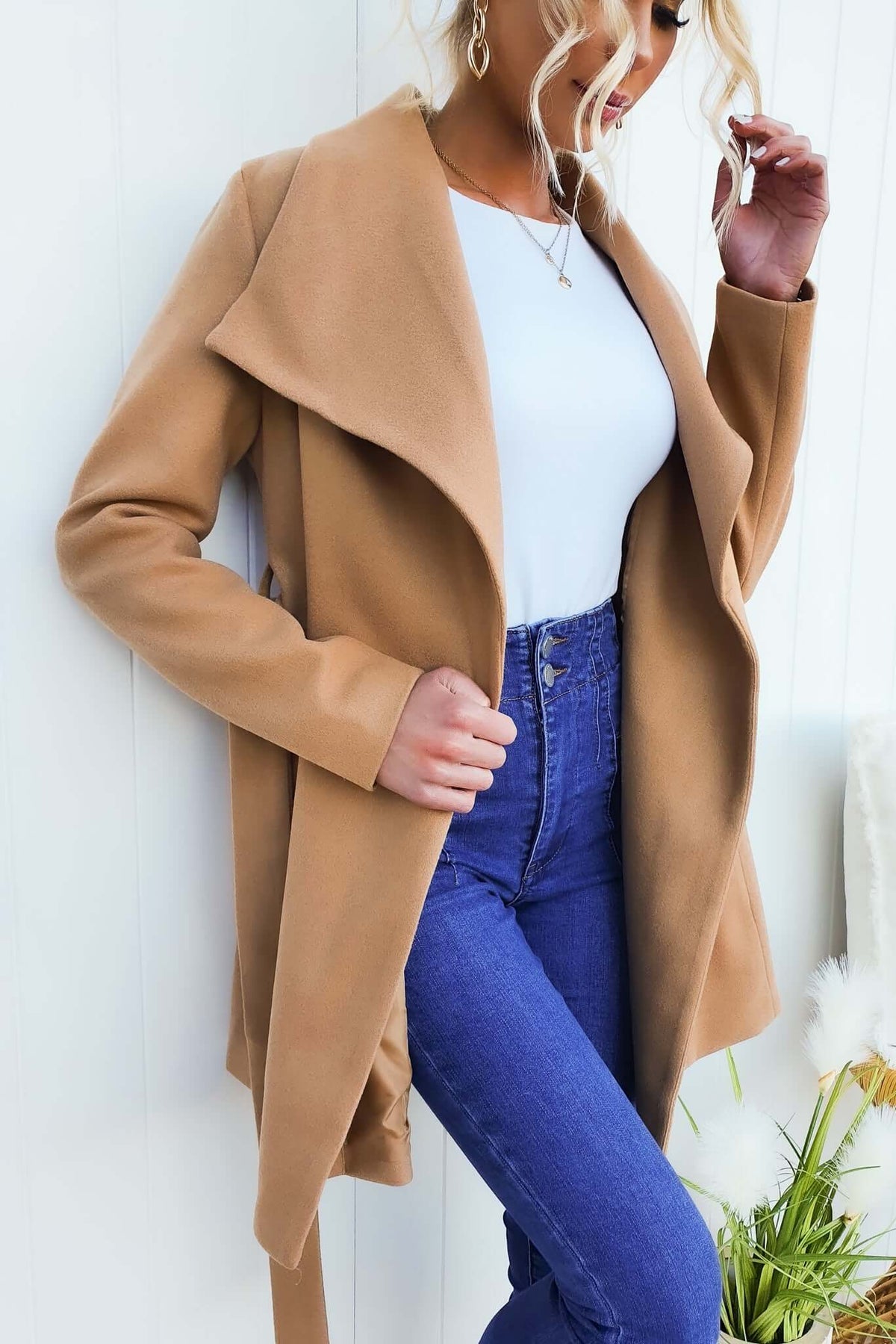 Woman wearing a tan Jean Coat over a white top, paired with high-waisted blue jeans.