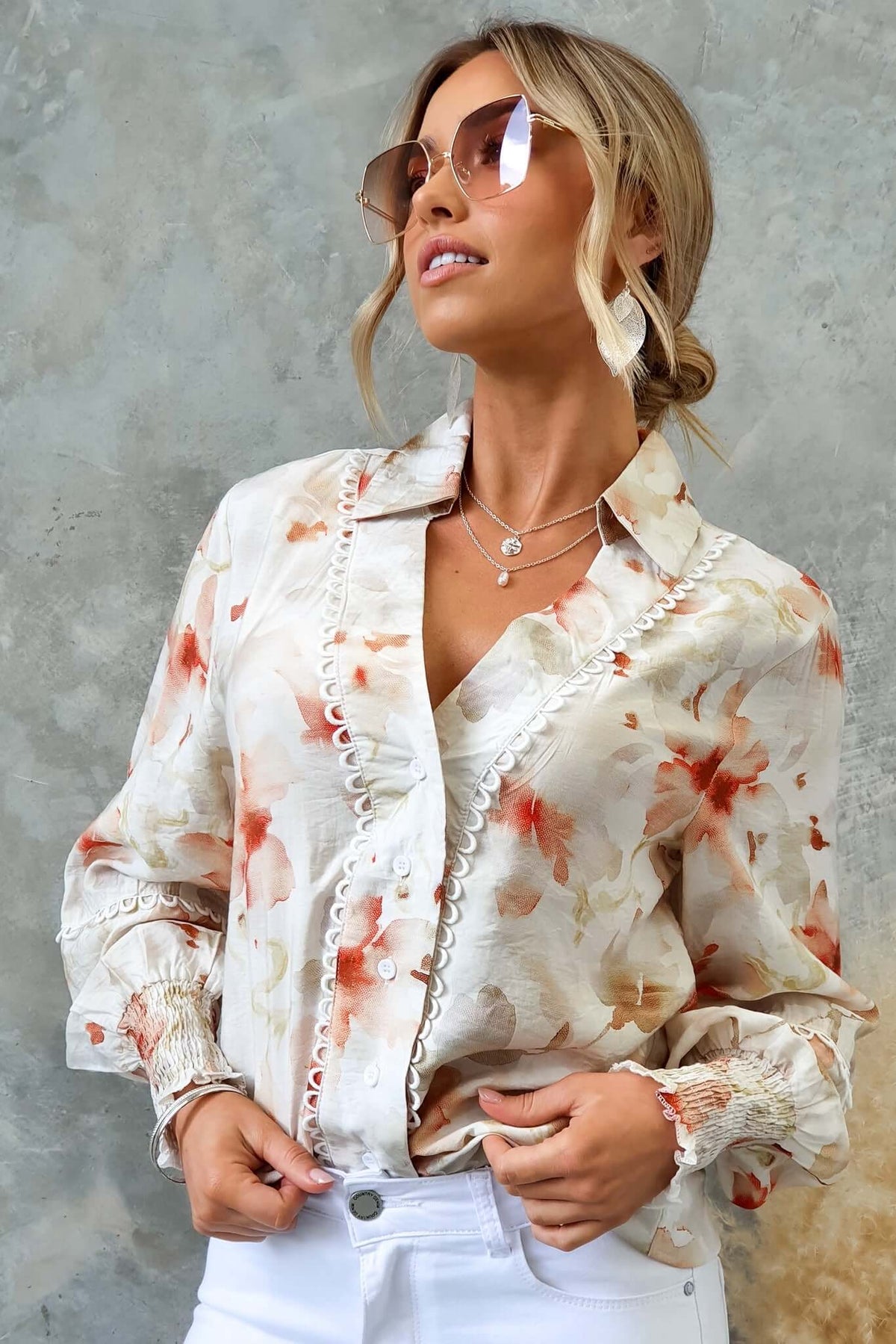Stylish model wearing Kellee Shirt with floral design, button-up front, and elastic cuffs, paired with sunglasses.