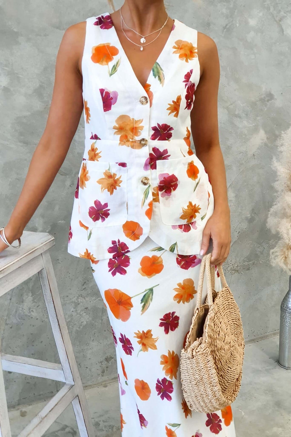 Model wearing Bexley Top, a floral vest style top with a V-neckline and button-up front, paired with a matching skirt.