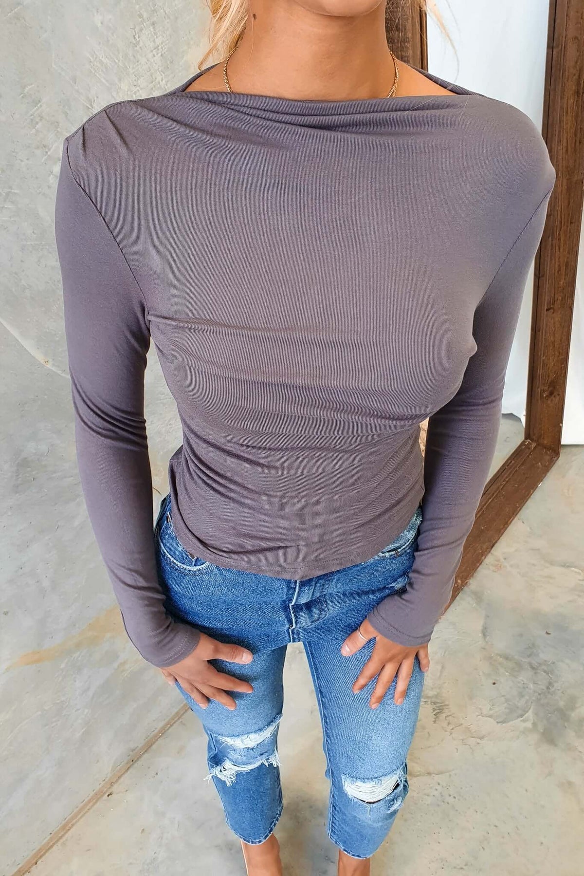 Iletta Top featuring a boat neckline, stitched detail, and stretchy material, paired with distressed jeans.