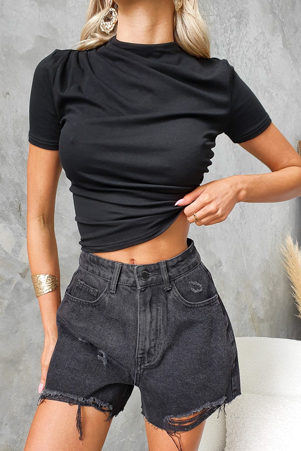 Black summer top with round neckline and side ruching, paired with distressed black shorts.