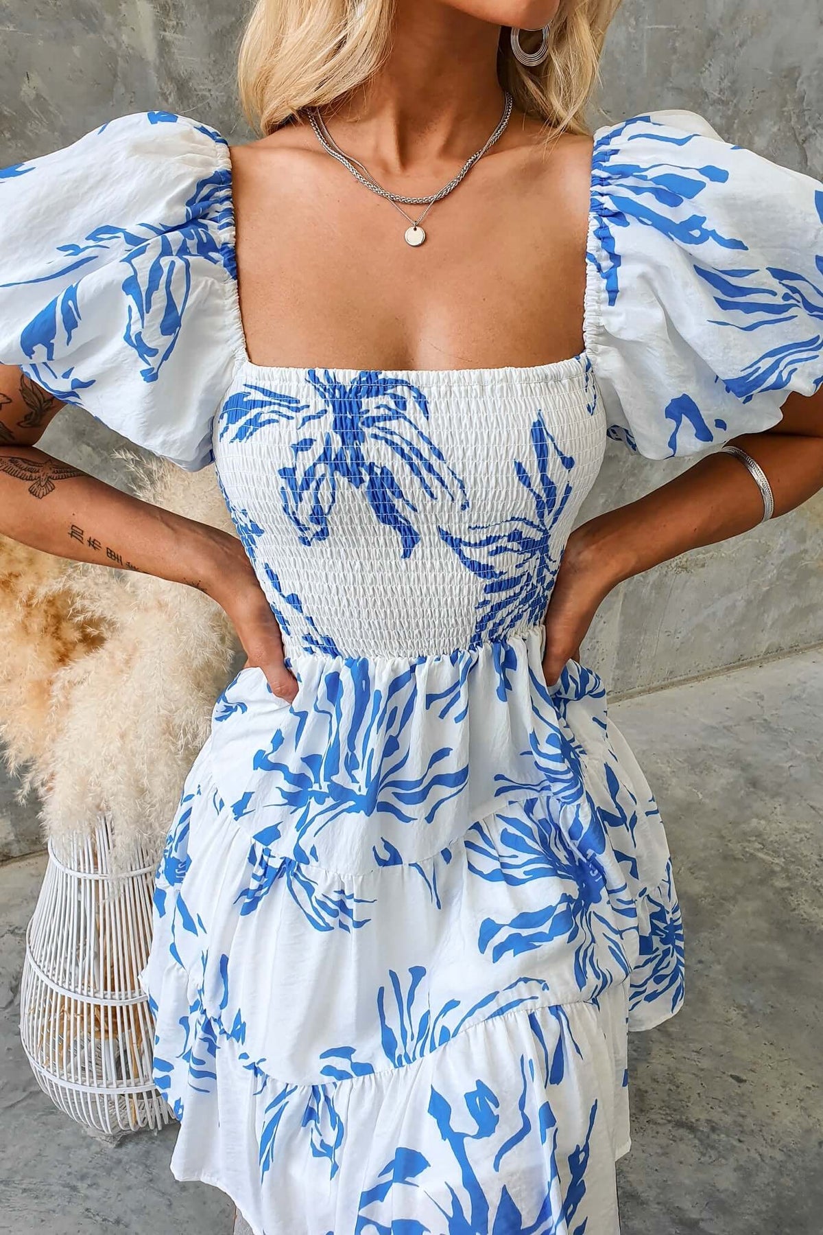 Blue Palms Dress featuring a shirred bodice, balloon sleeves, and floral blue print, perfect for summer outings.
