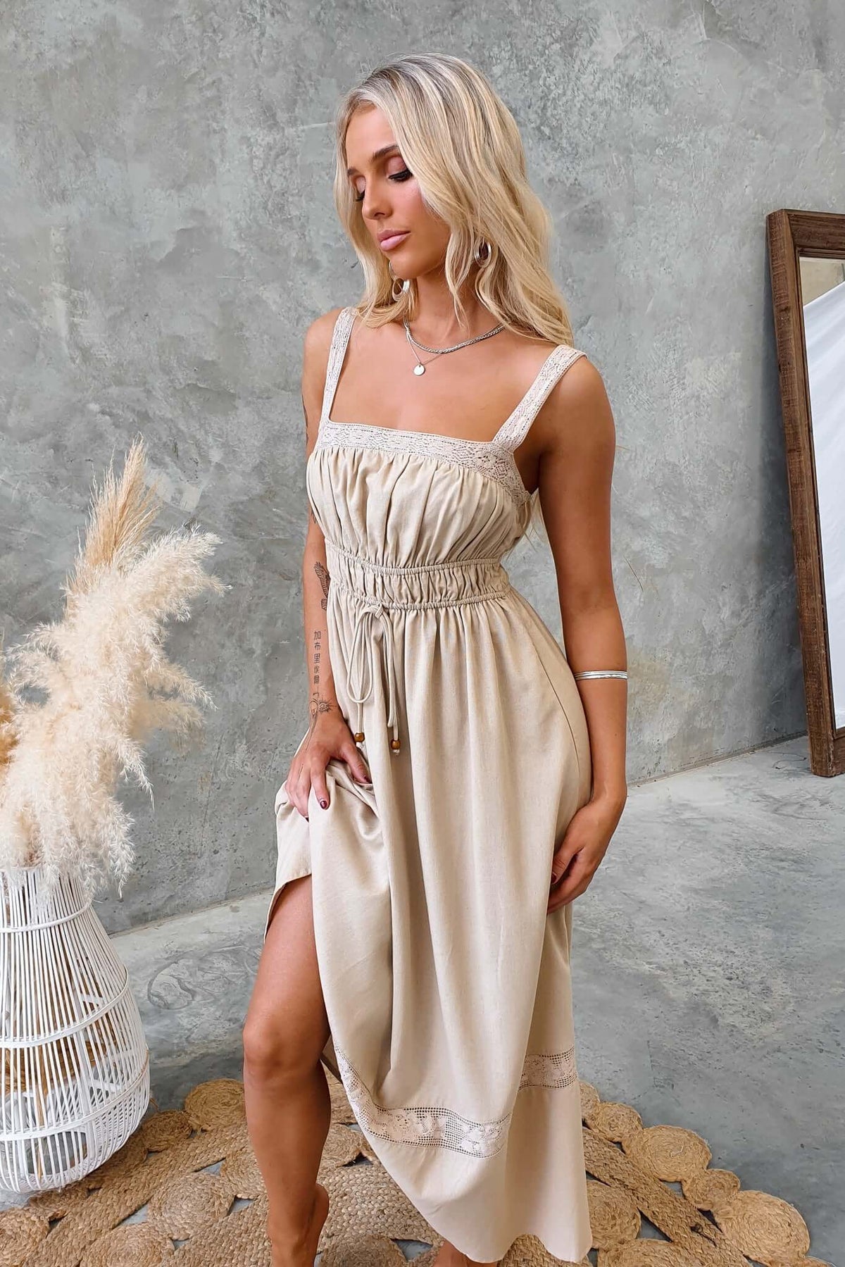 Model wearing Eletti Midi Dress with lace detailing and tie waist in a stylish indoor setting.