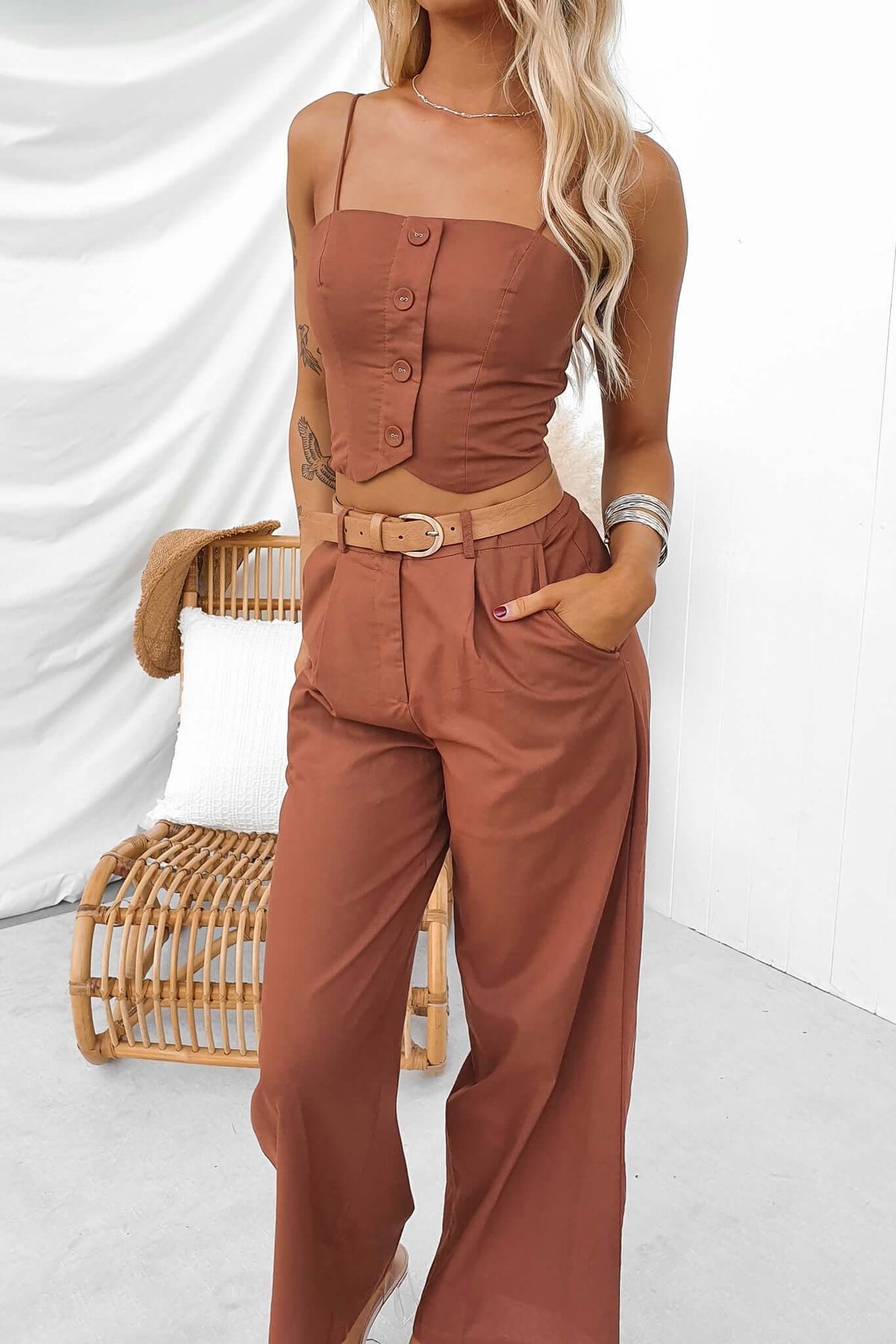 Fashionable woman wearing Downtown Top with adjustable straps and button front, paired with stylish high-waisted pants.