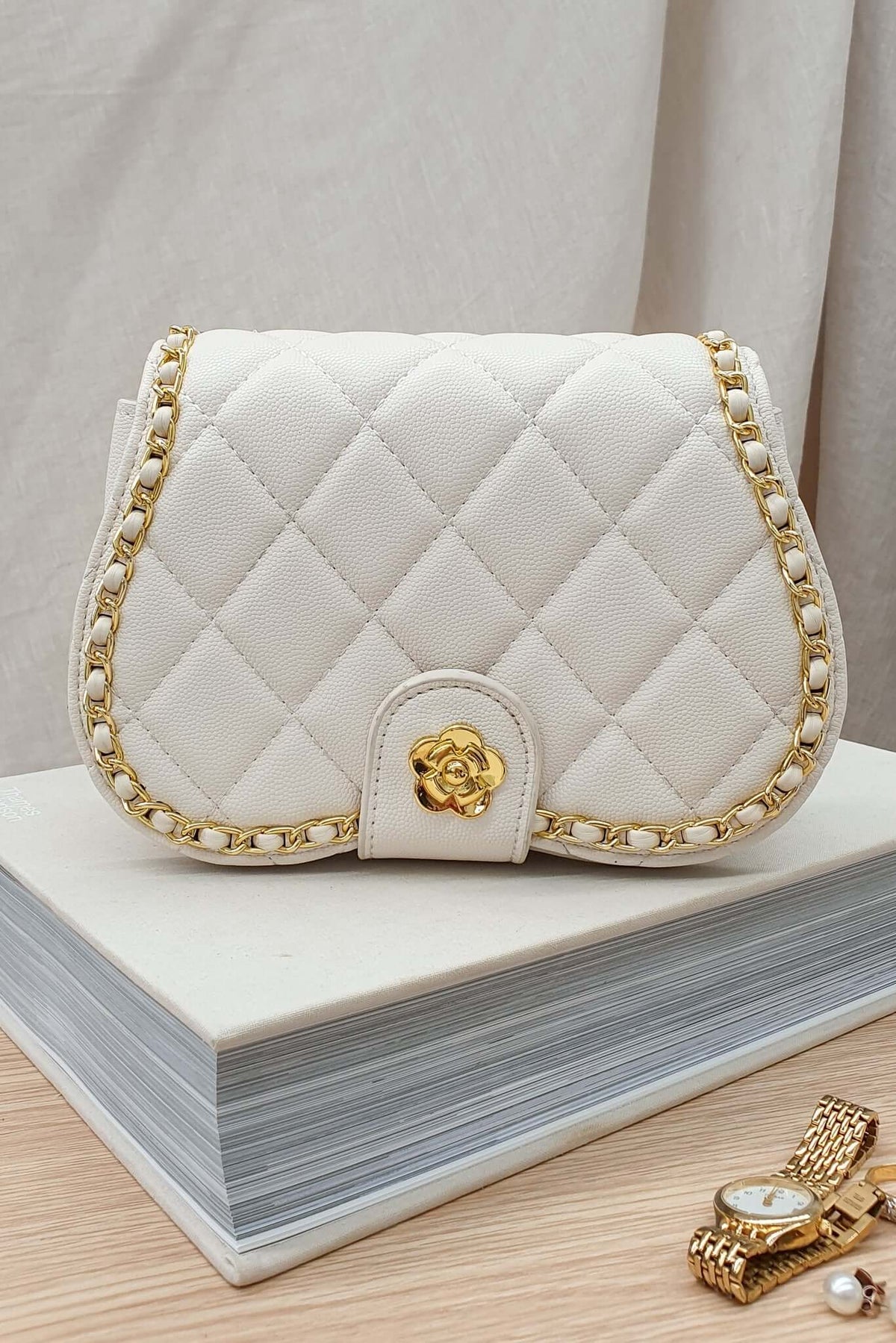 Chic white Vera Bag with quilted design and gold chain details, perfect for complementing any outfit.