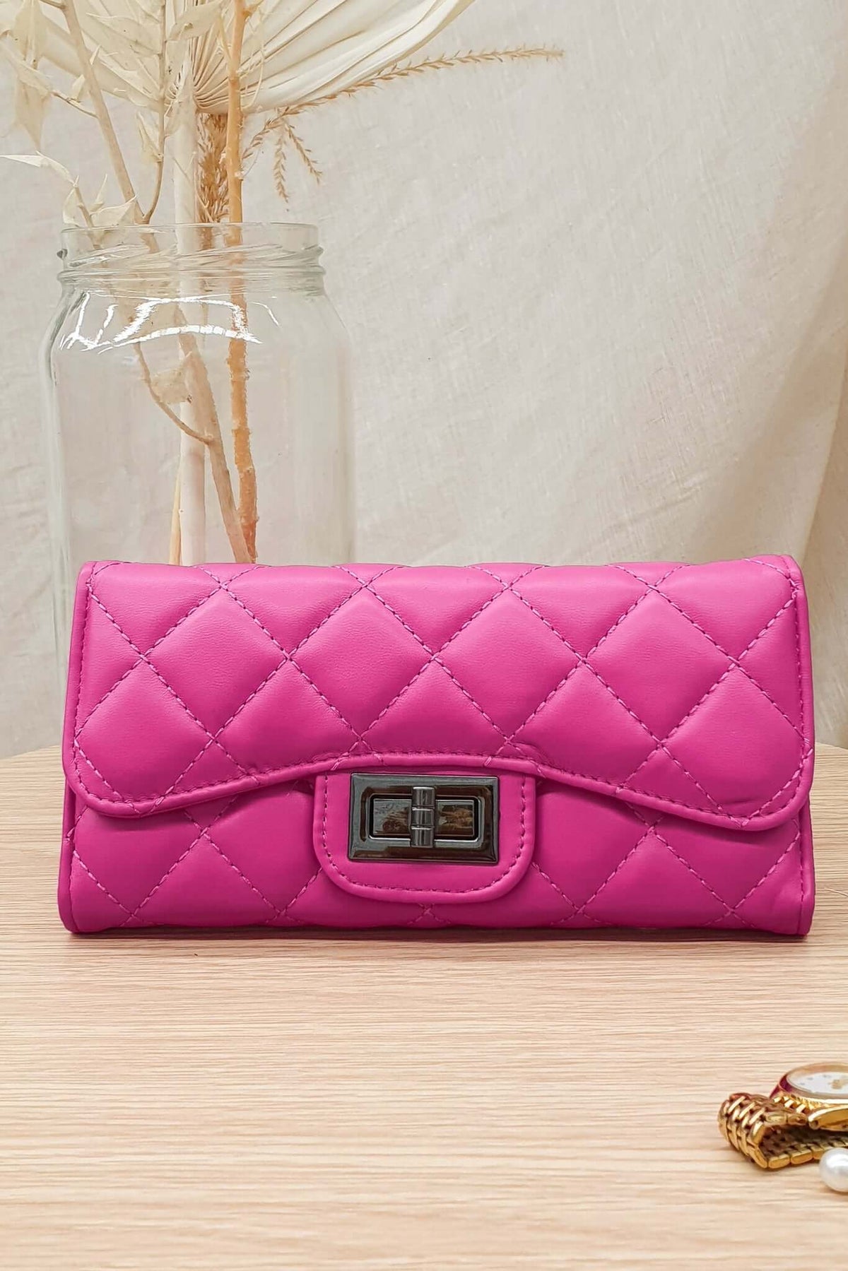 Asta Wallet in vibrant pink vegan leather with quilted design, featuring a metal clasp and elegant styling for day and night.
