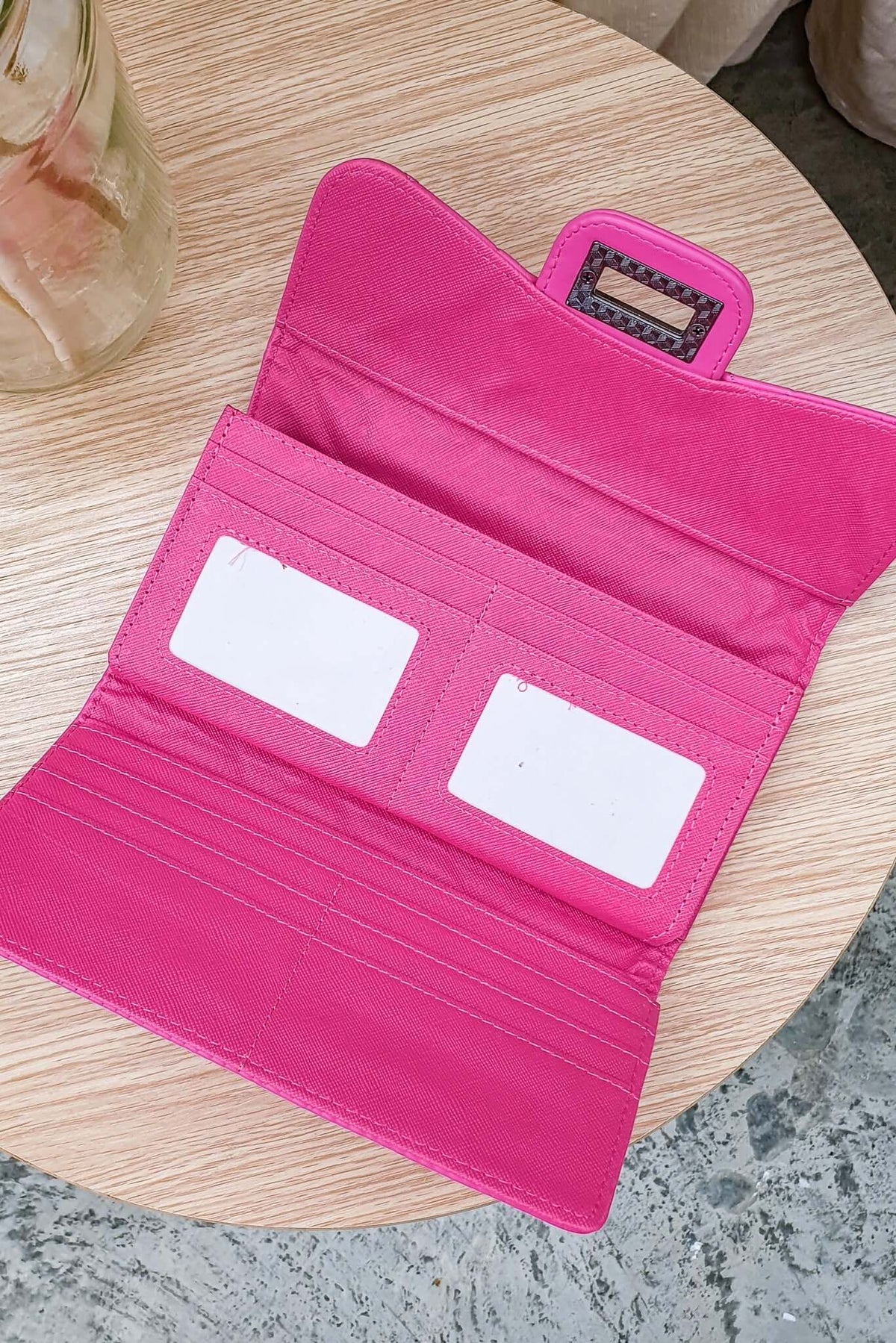 Inside view of Asta Wallet featuring vibrant pink vegan leather, card slots, and ID windows on a wooden table.