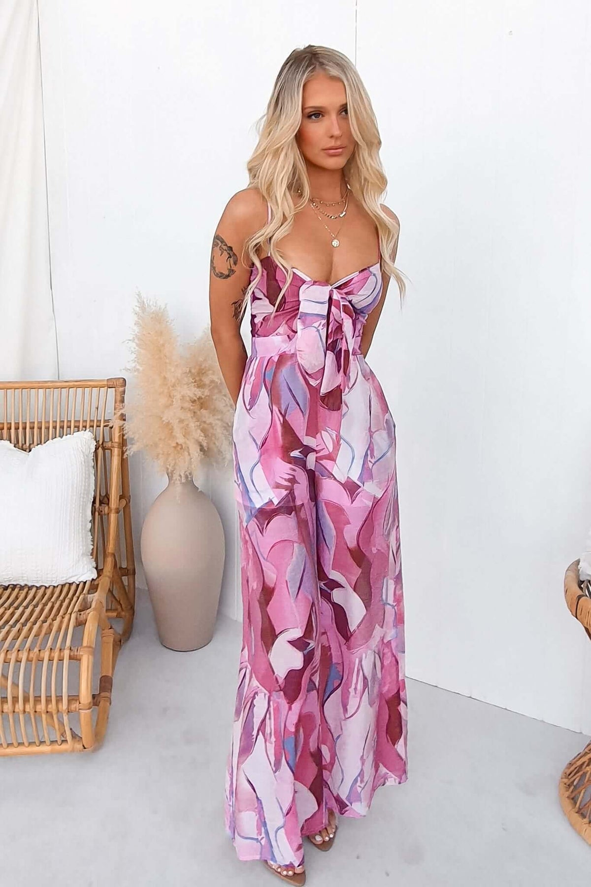 Model wearing a multi-colour print Sun Dazed Jumpsuit with adjustable straps and tie detail.